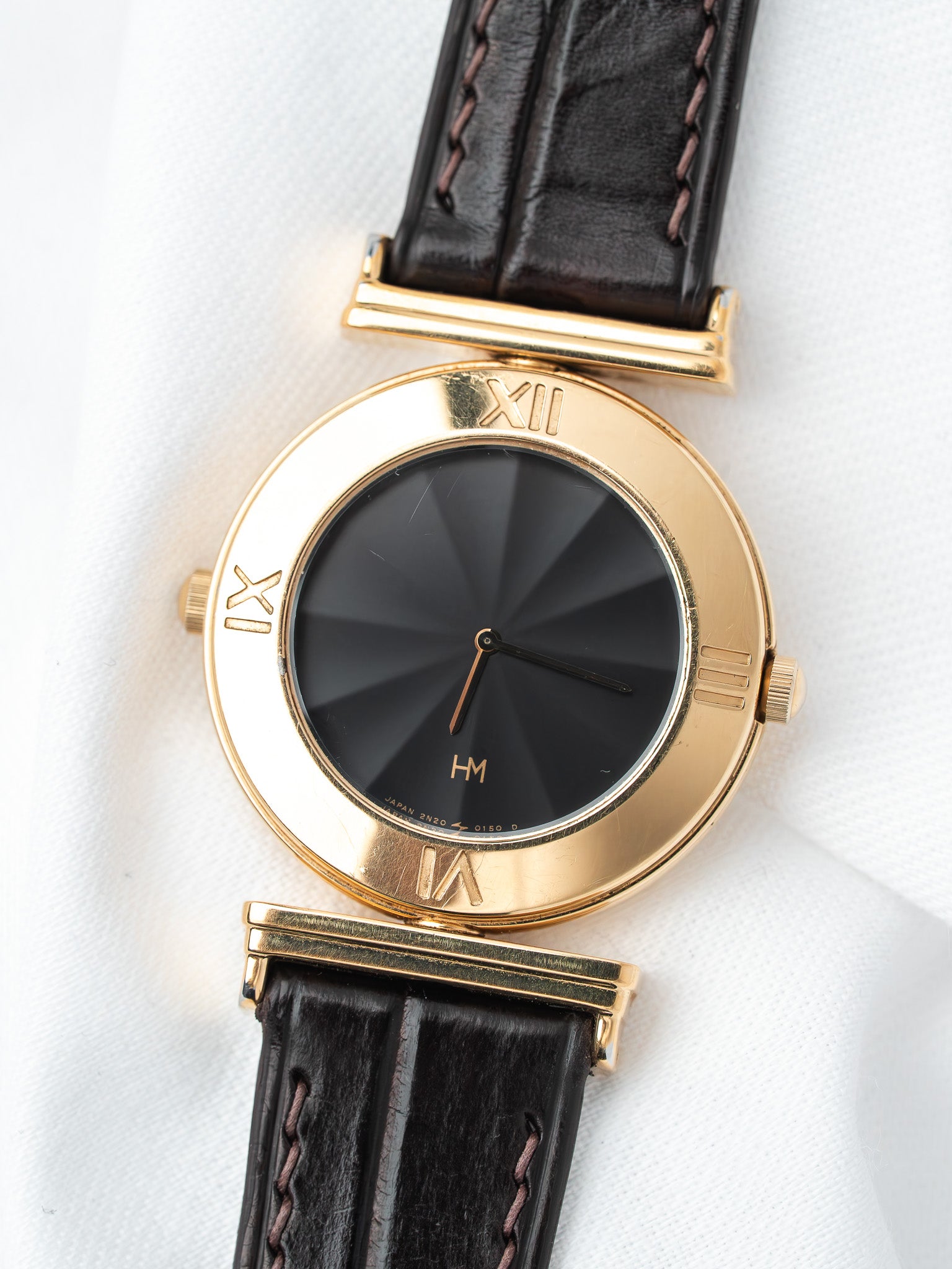 HM vintage watch with gold case, black dial, and brown leather strap