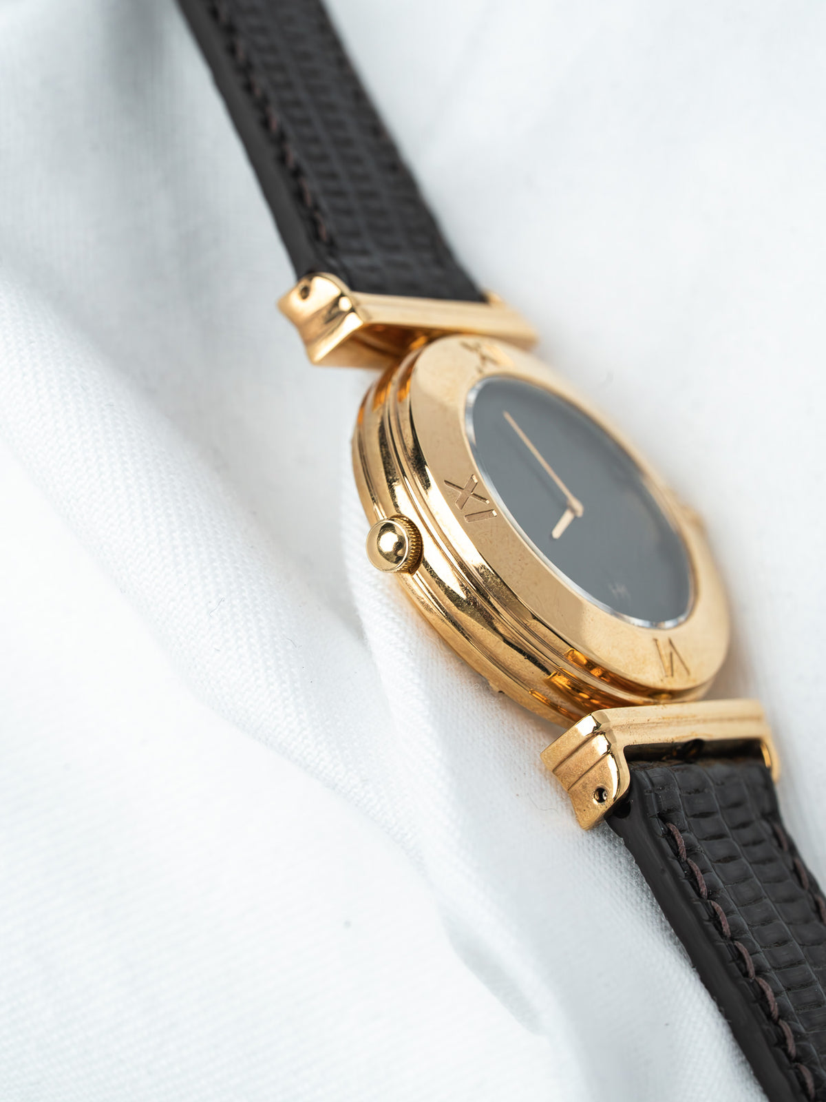 Vintage Cartier watch with gold case, black dial, and textured leather strap