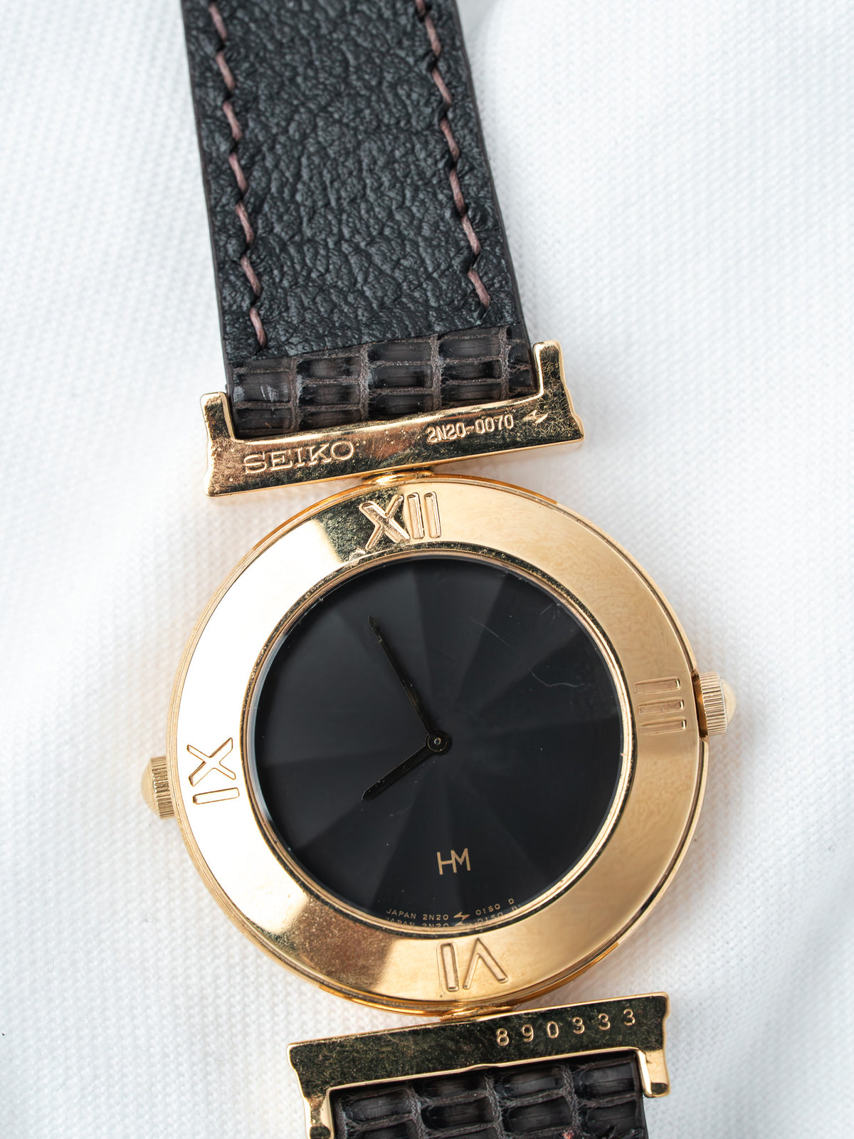 Seiko vintage watch with gold case, black dial, Roman numerals, and black leather strap