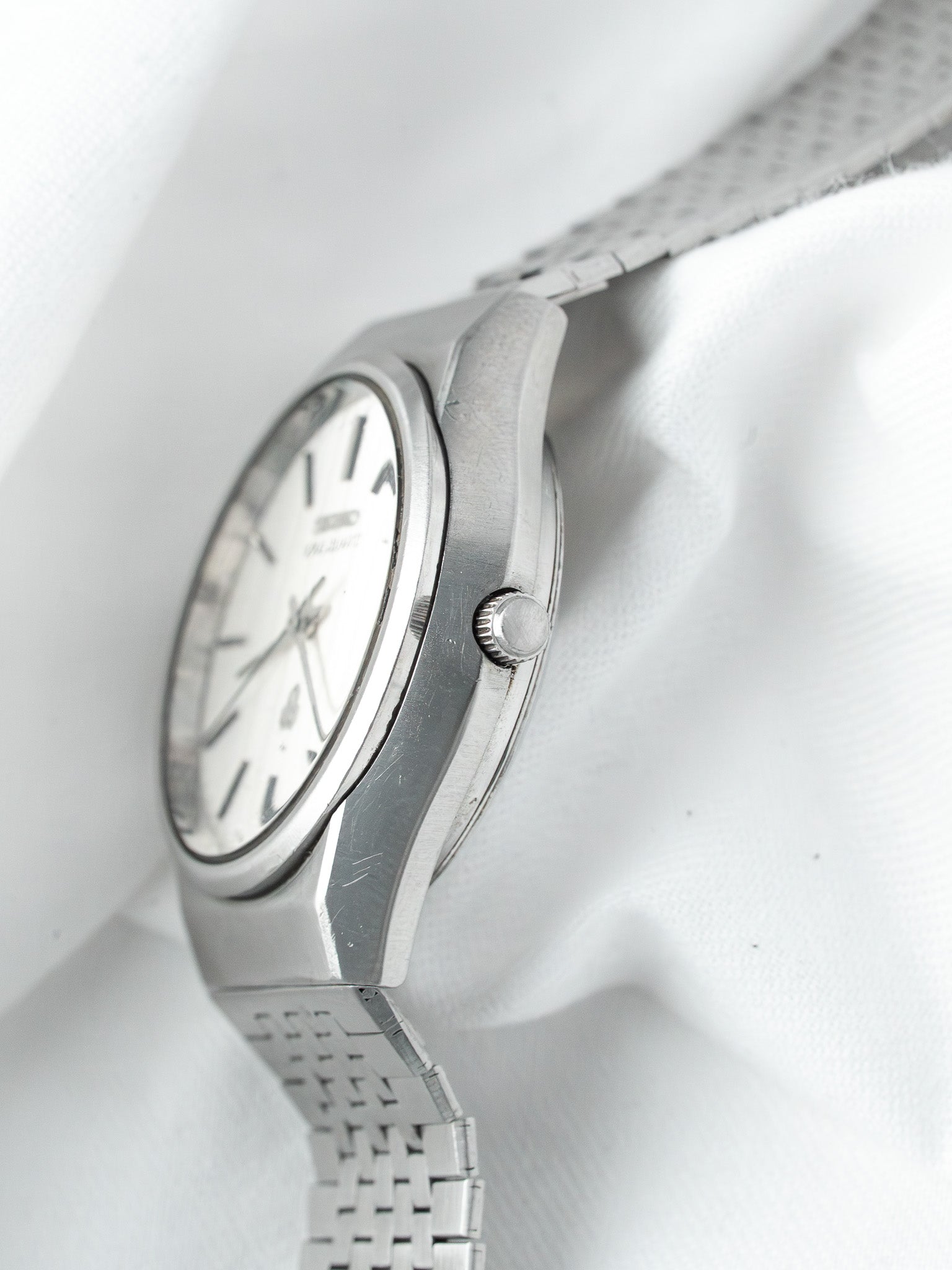 Seiko vintage watch with white dial, steel case and mesh bracelet on white fabric