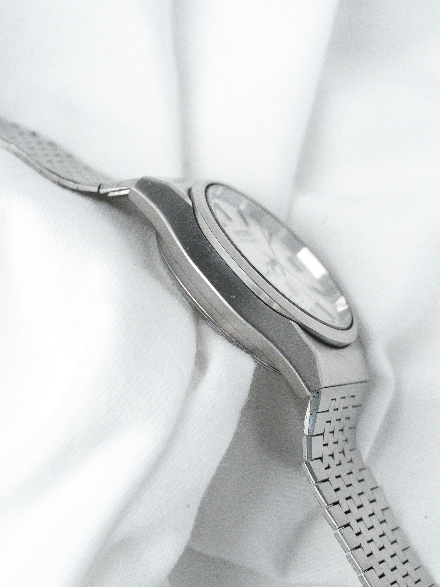 Vintage Omega Constellation watch with steel mesh bracelet, silver dial, on white fabric