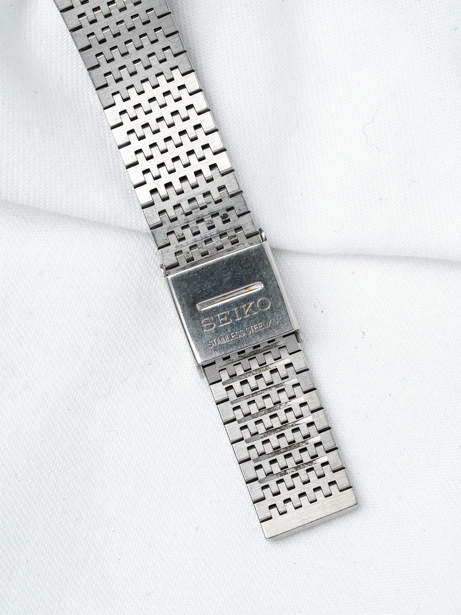 Seiko vintage stainless steel bracelet with distinctive woven link pattern on white fabric
