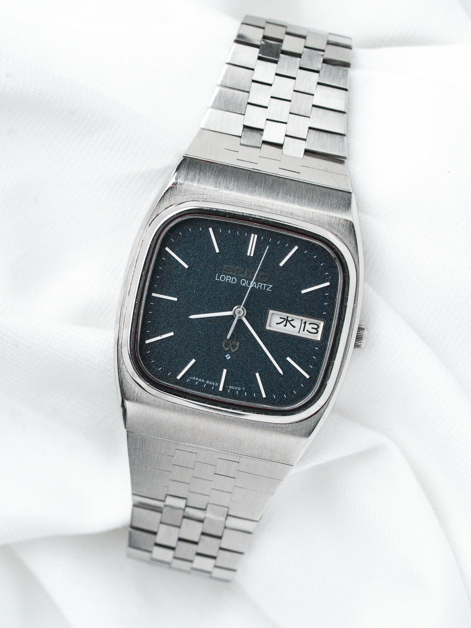 Seiko Lord Quartz vintage watch with black dial, steel bracelet, day-date display on white fabric