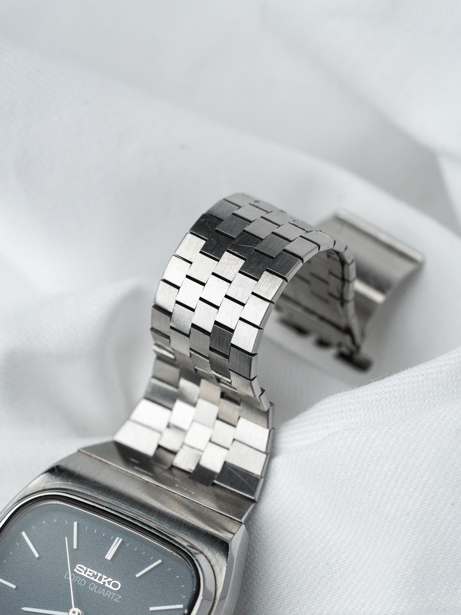 Seiko Lord Quartz vintage watch with gray dial and stainless steel bracelet on white fabric