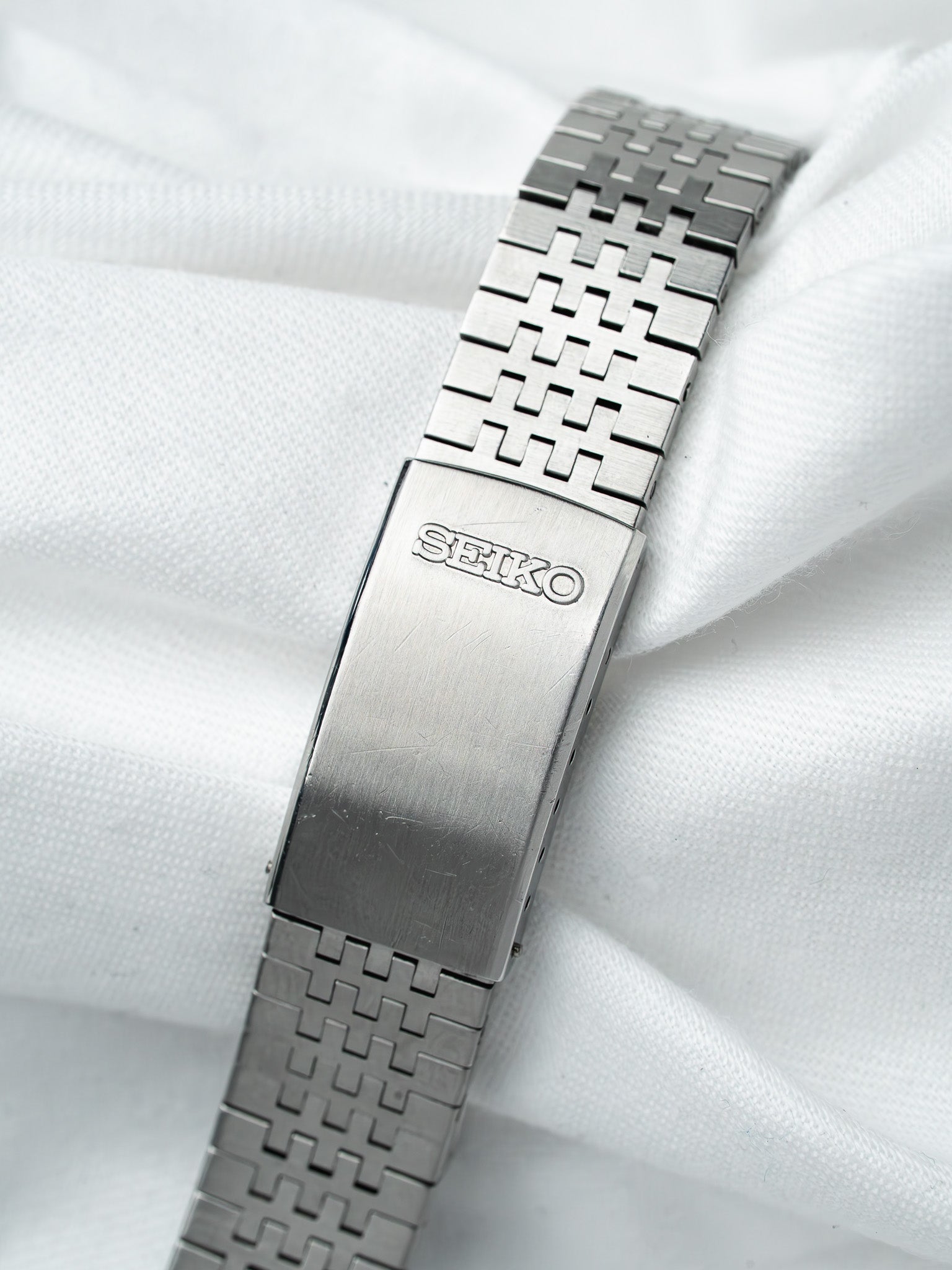 Seiko vintage watch bracelet with intricate metal links on white fabric