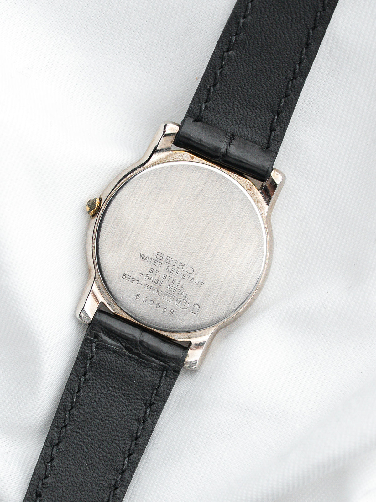 Dos en acier inoxydable d'une montre Seiko avec un bracelet en cuir noir.