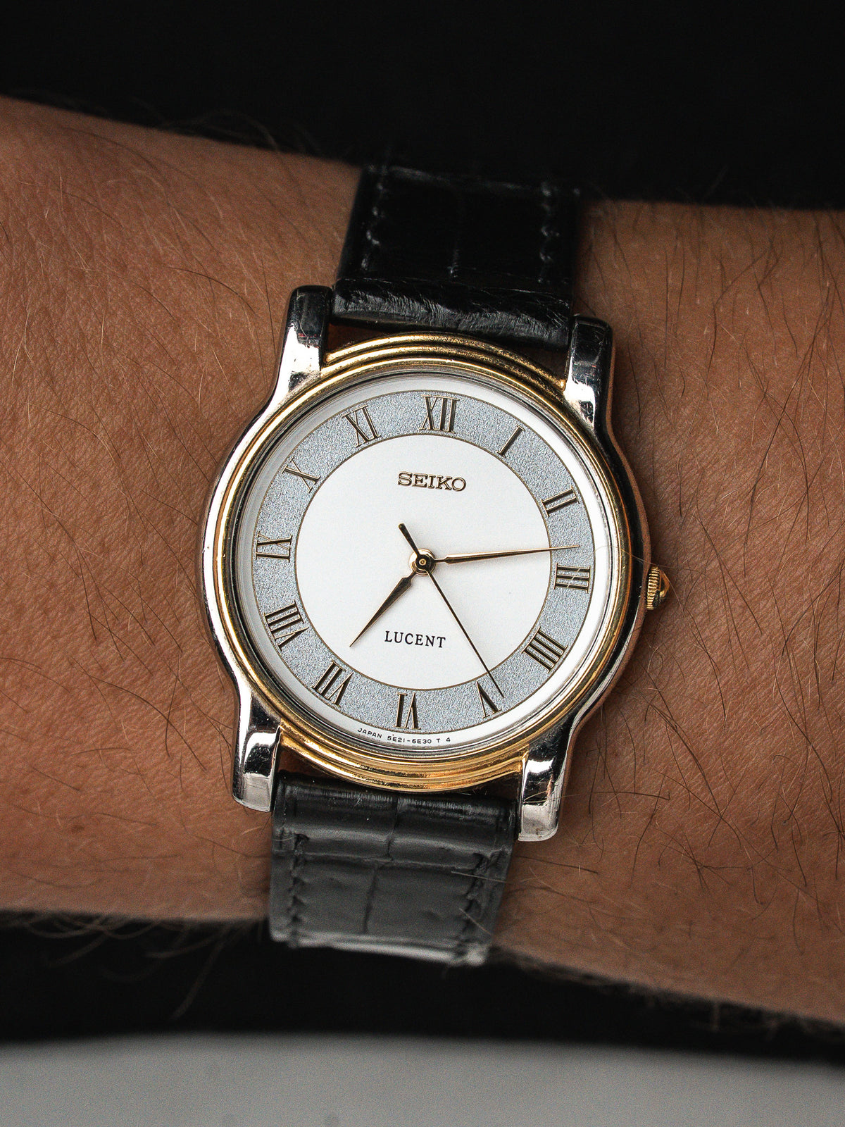 Montre Seiko Lucent vintage avec cadran blanc, chiffres romains et bracelet en cuir noir.