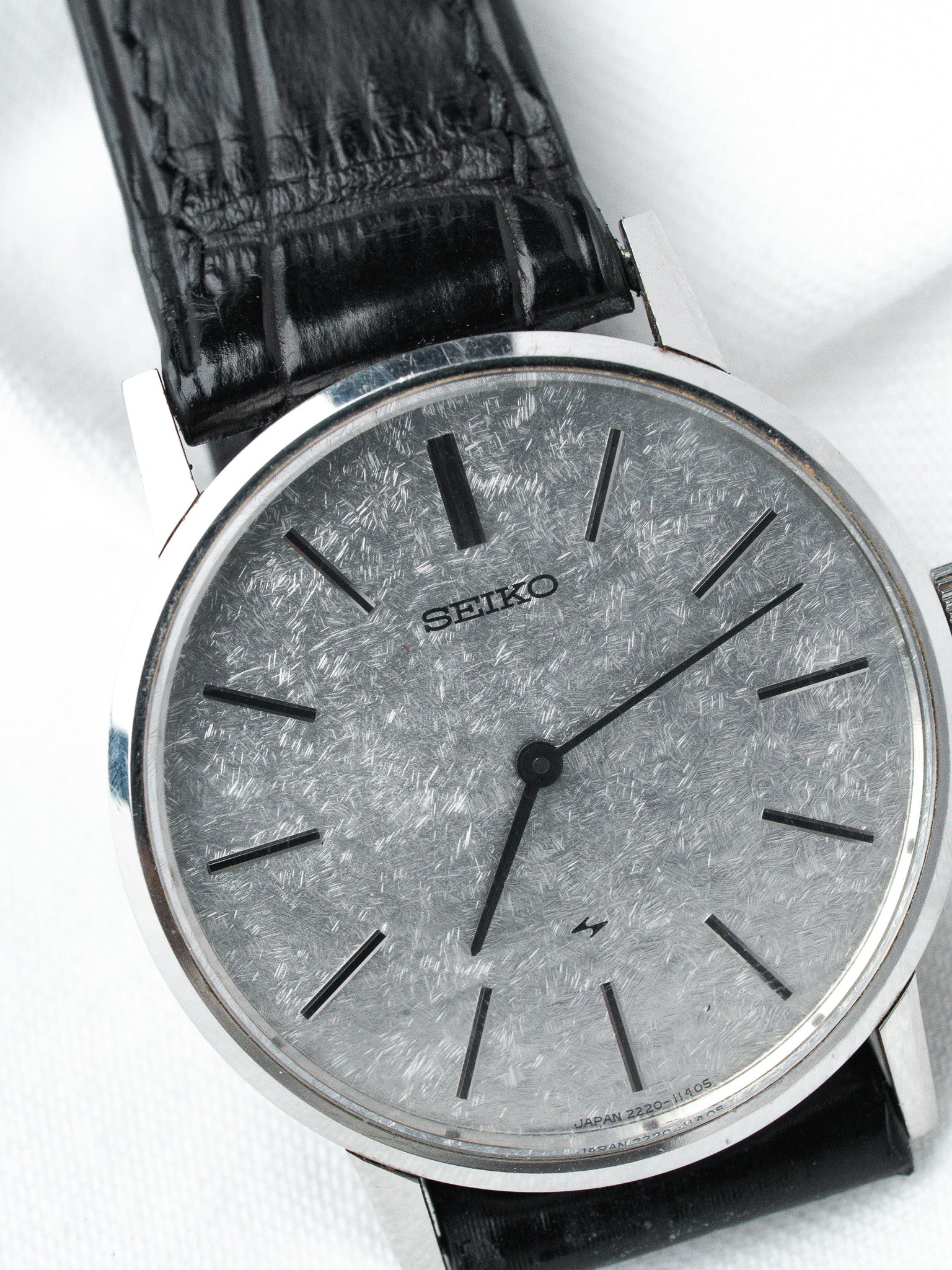 Seiko vintage watch with silver textured dial, black markers, and black leather strap