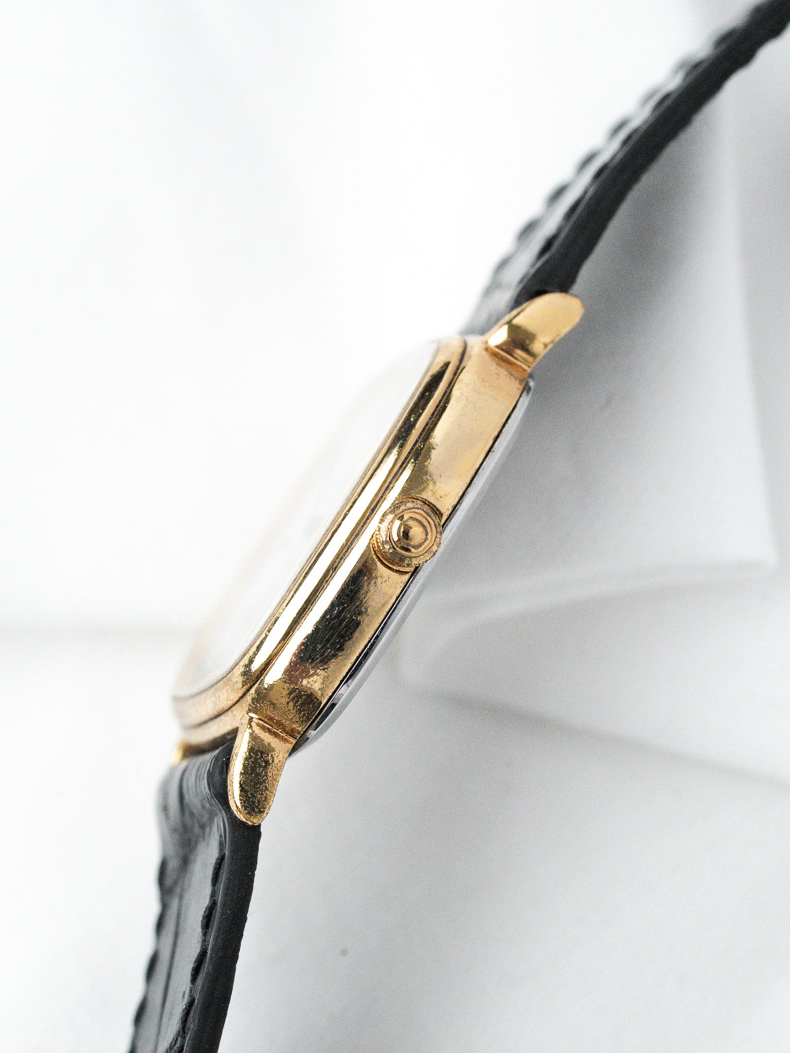 Vintage Cartier watch with gold case and black leather strap, side view