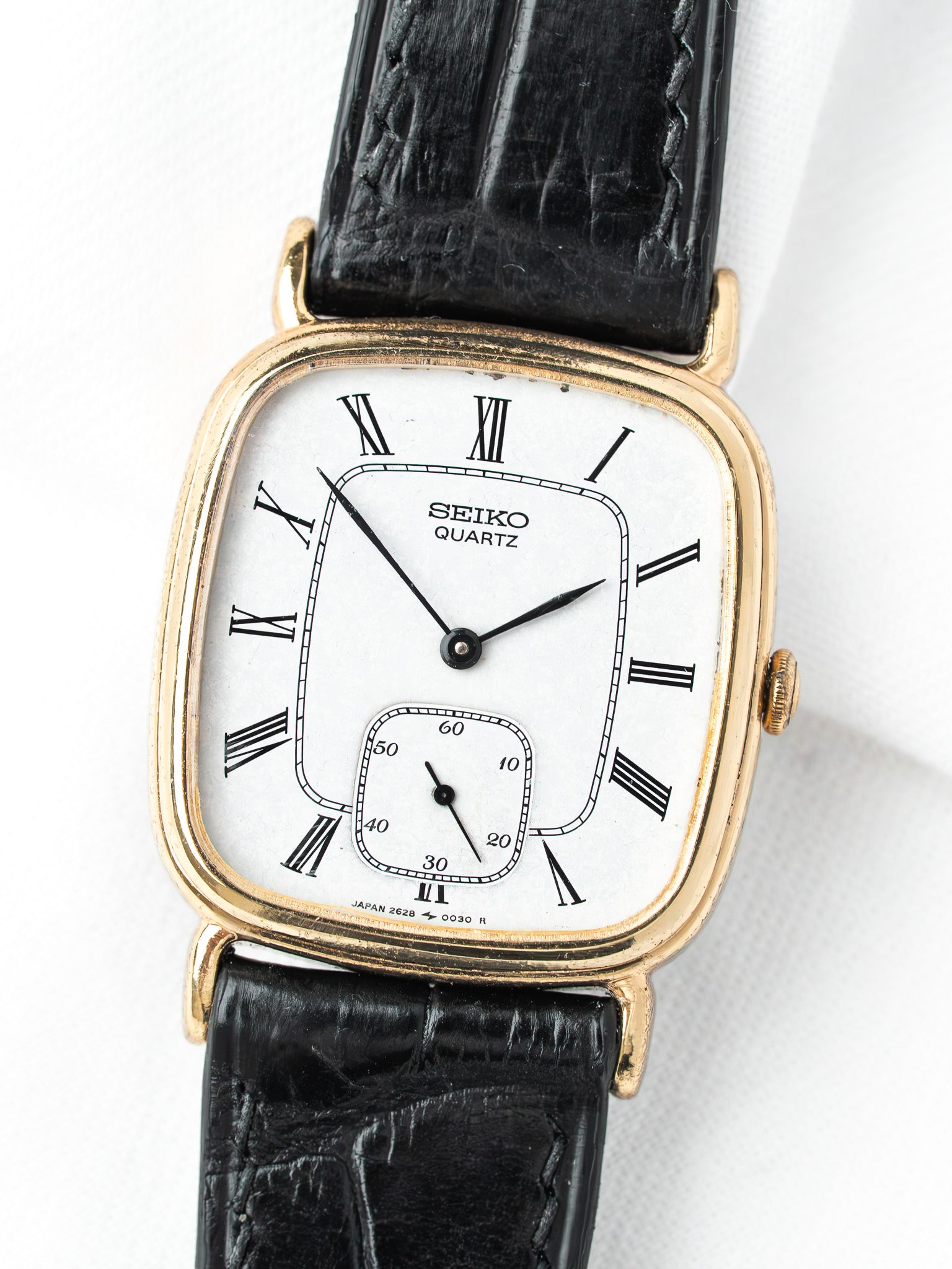 Seiko Quartz vintage watch with gold case, white dial, Roman numerals, black leather strap