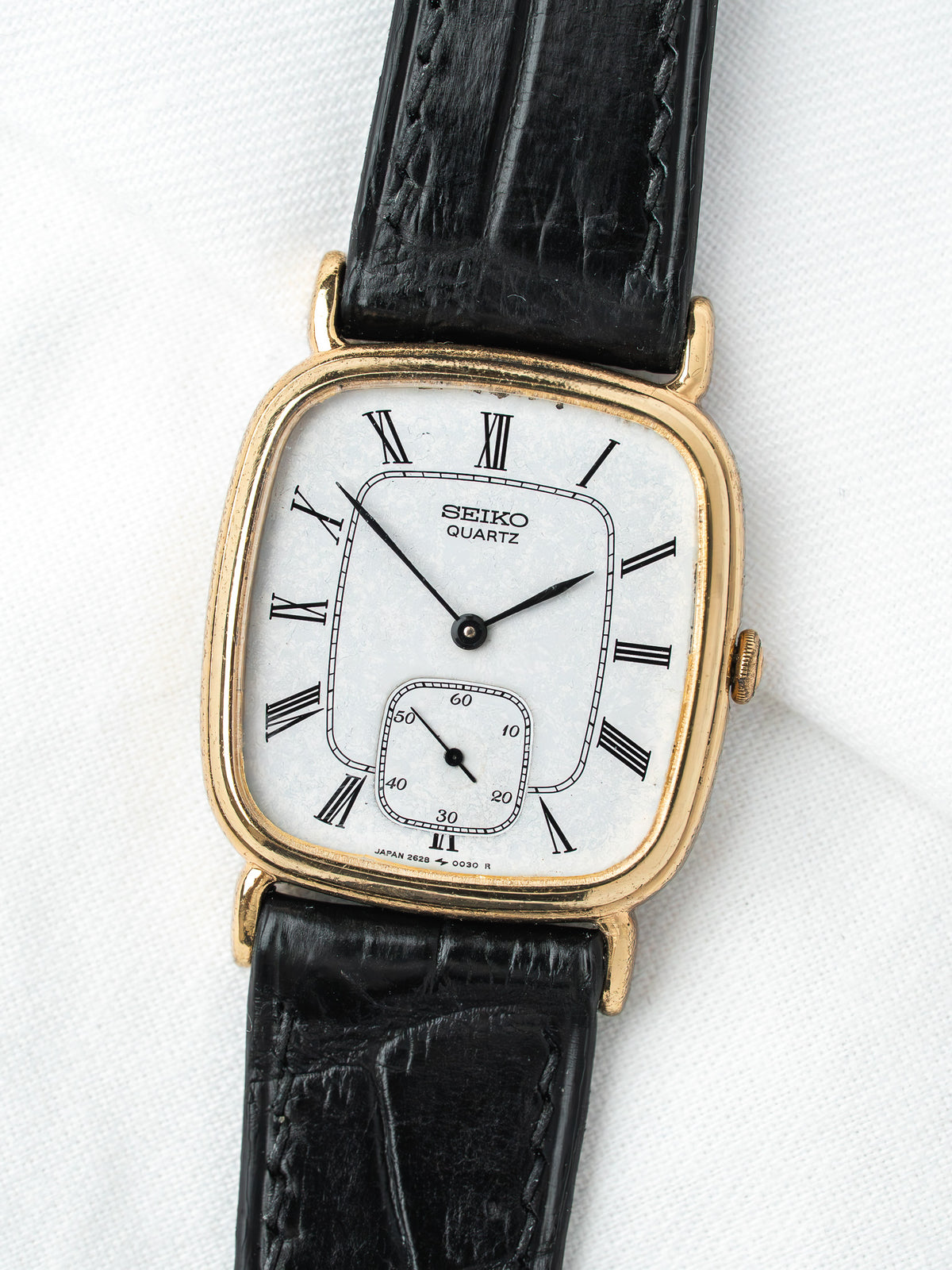 Seiko Quartz vintage watch with gold case, white dial, Roman numerals, black leather strap