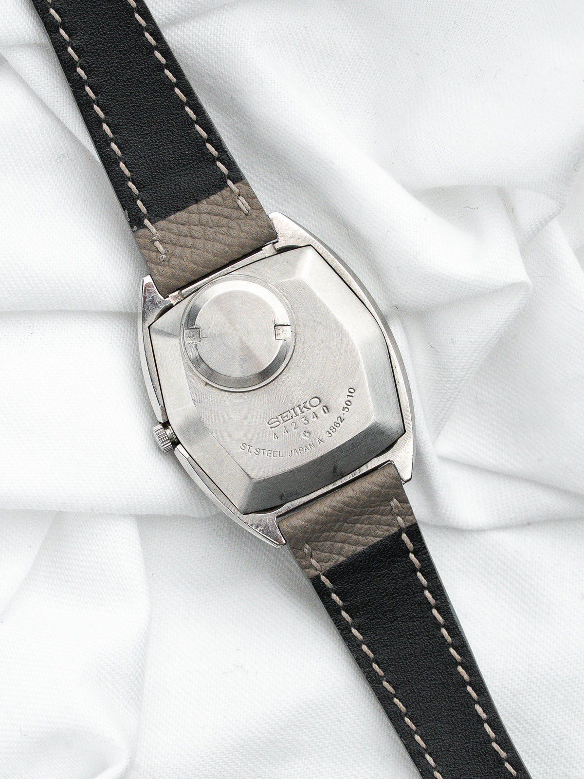 Dos d'une montre Seiko vintage en acier avec bracelet en cuir noir et gris