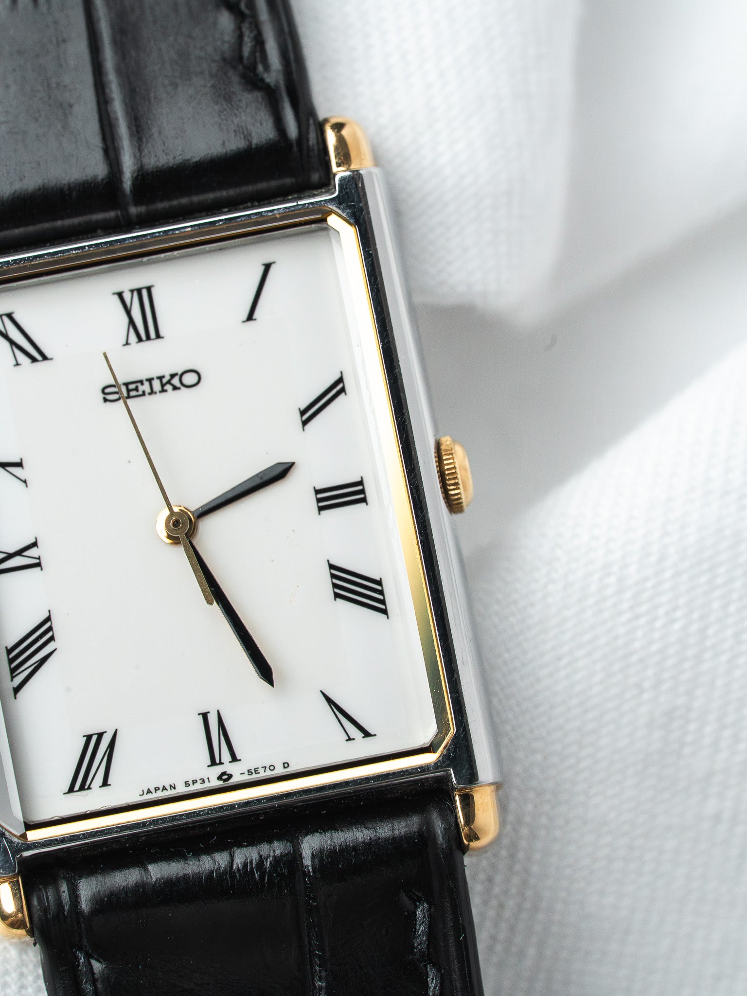 Seiko vintage watch with white dial, Roman numerals, gold accents, black leather strap