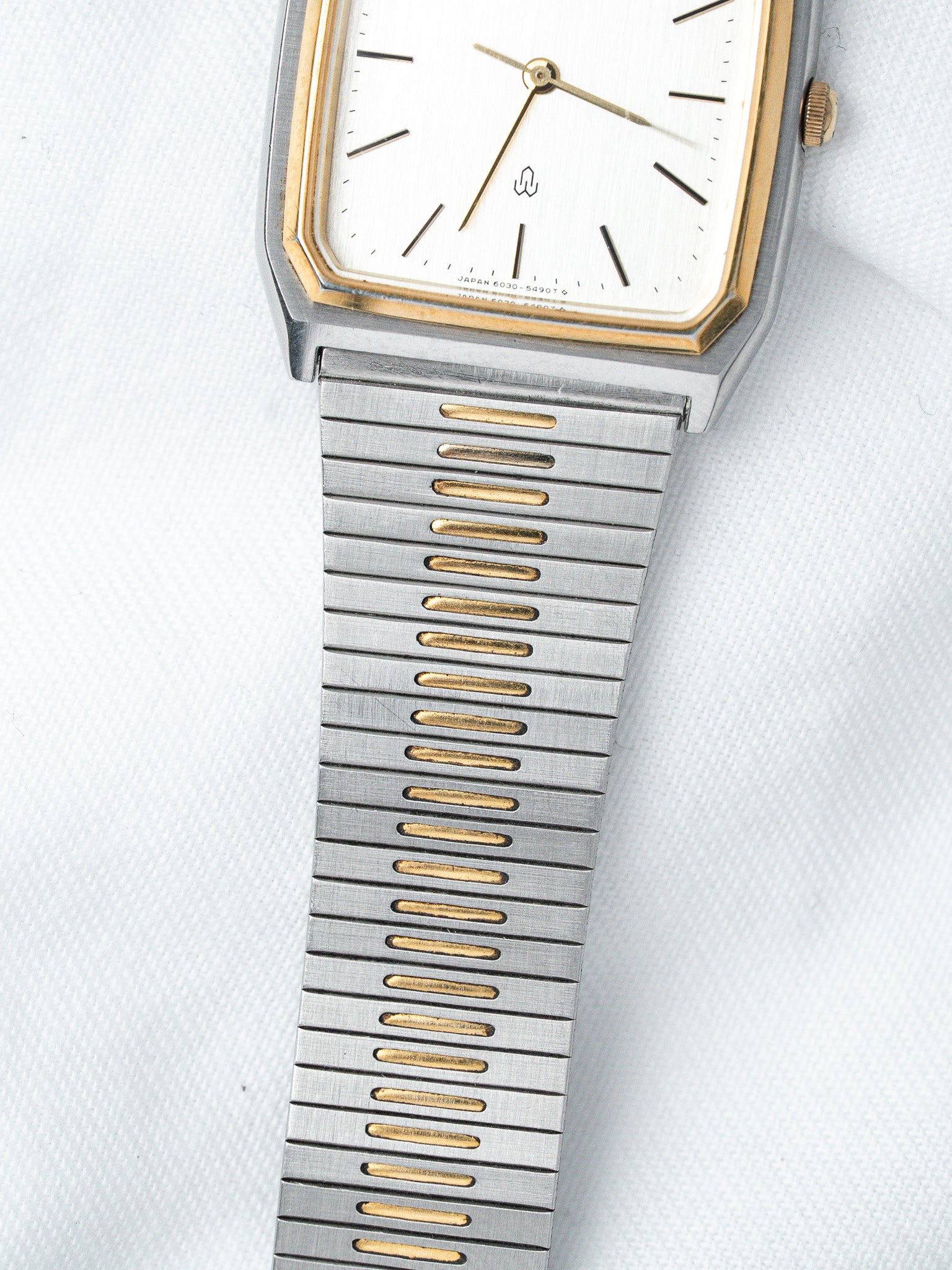 Vintage Seiko watch with white dial, gold accents, and two-tone metal bracelet on white background