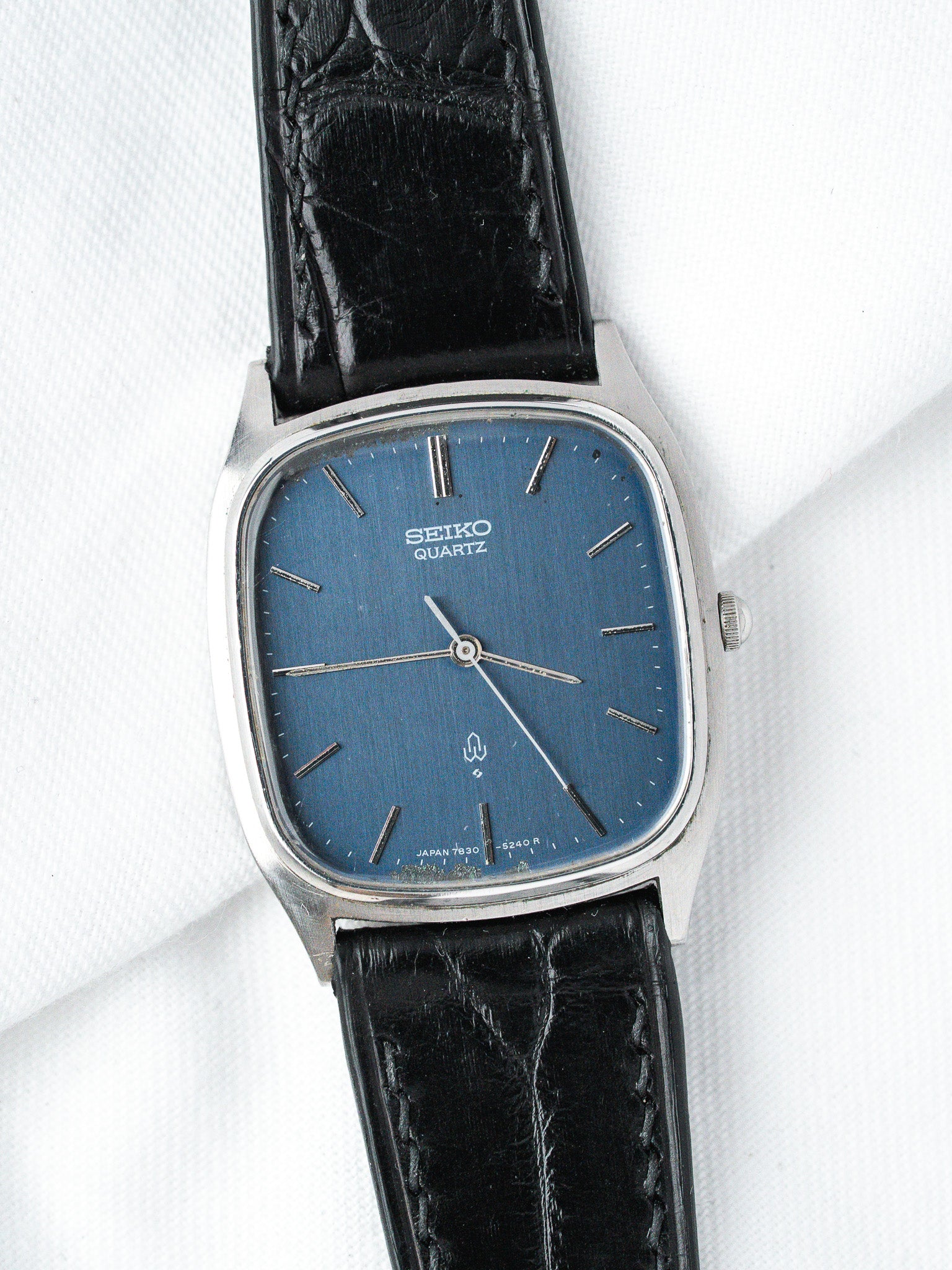 Seiko Quartz vintage watch with blue dial, silver case, black leather strap on white background