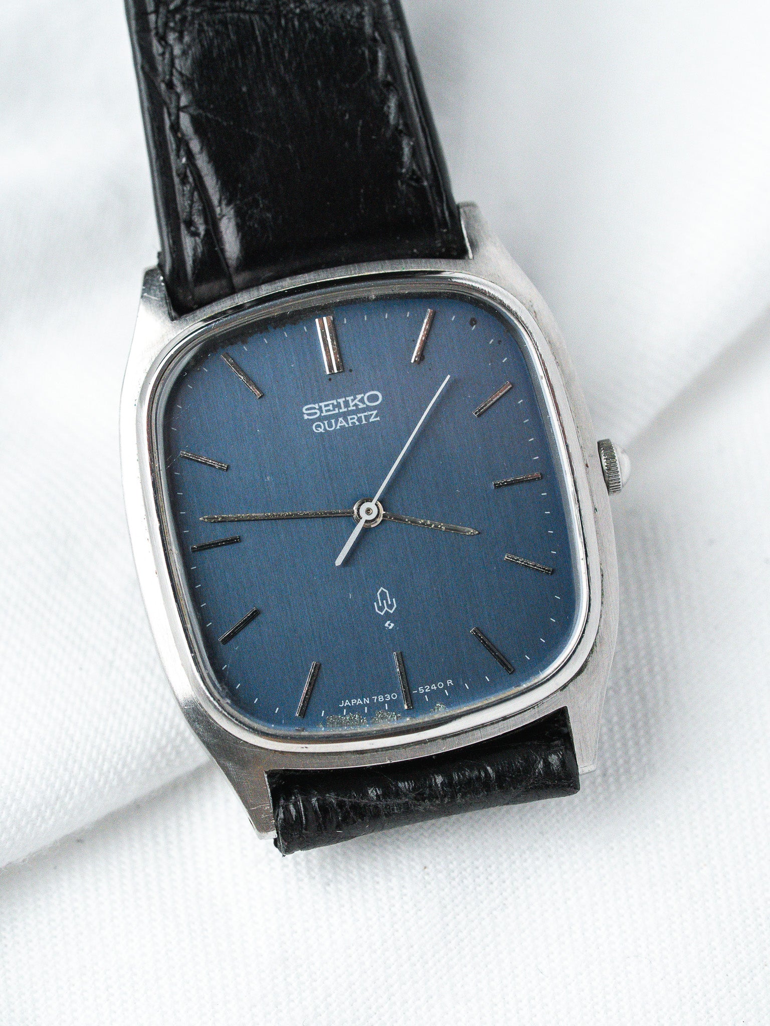 Seiko Quartz vintage watch with blue dial, steel case, black leather strap on white background