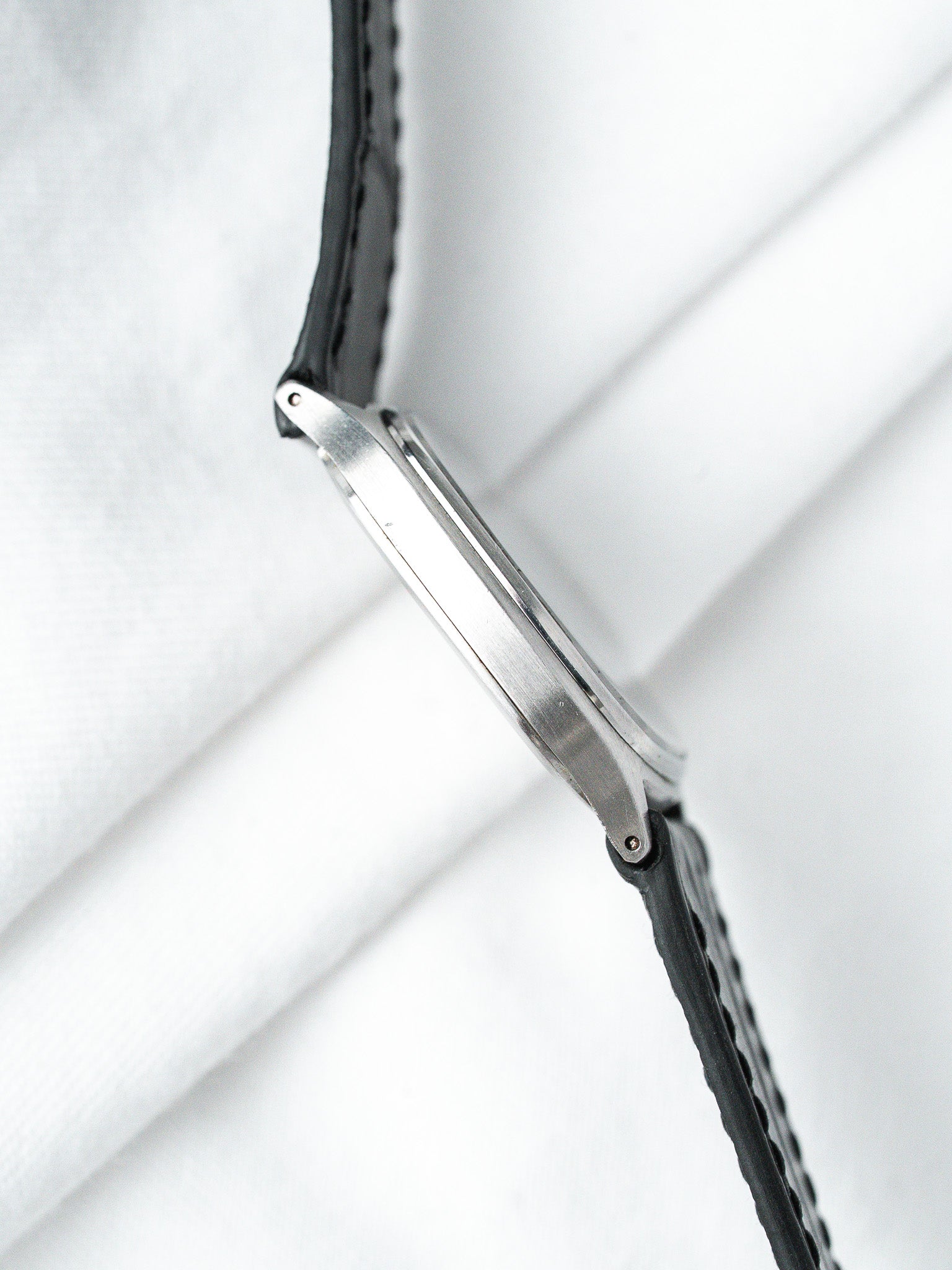Vintage Omega watch with stainless steel case and black leather strap on white background