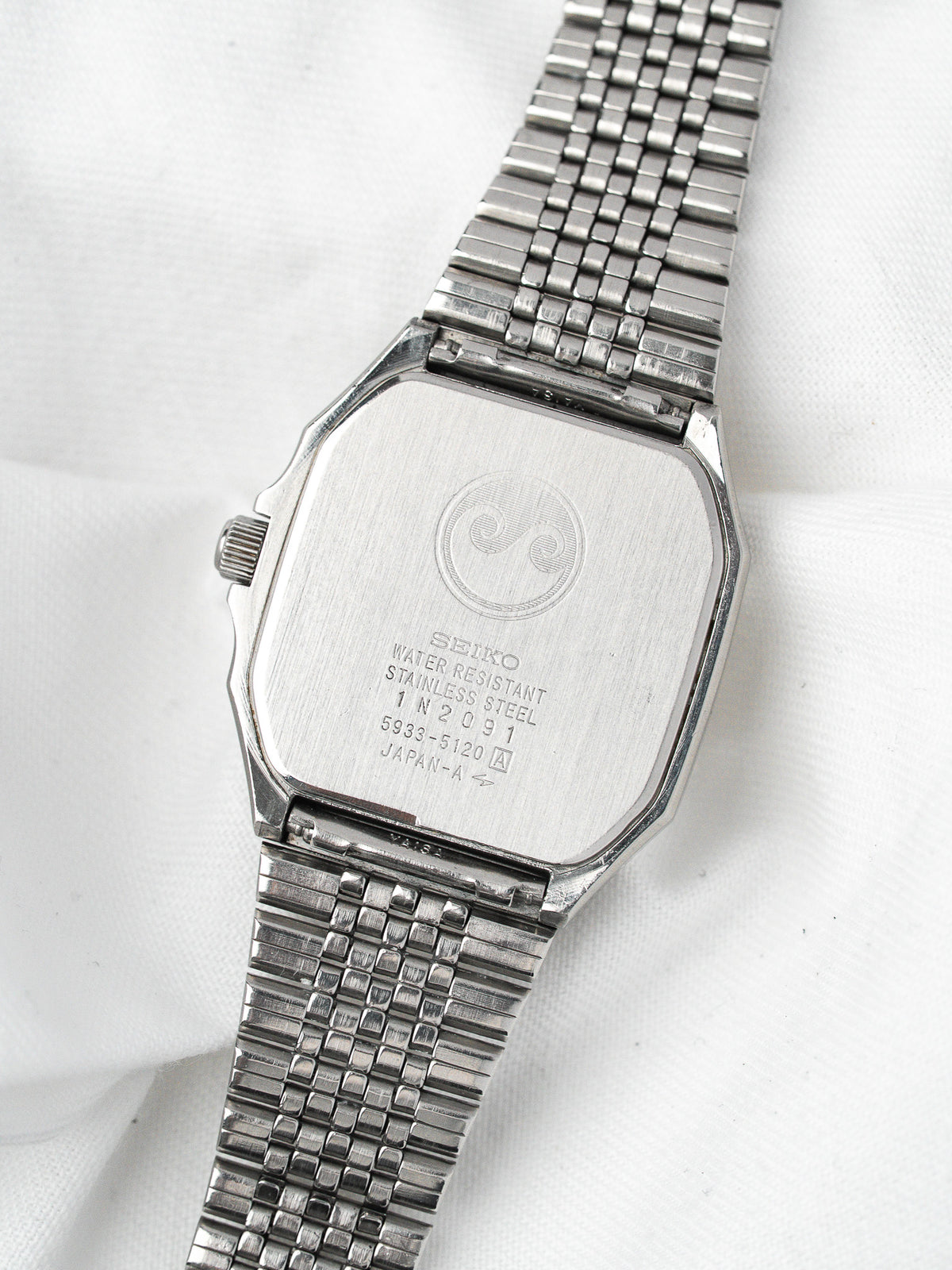 Seiko vintage watch with stainless steel case and mesh bracelet, back view on white background