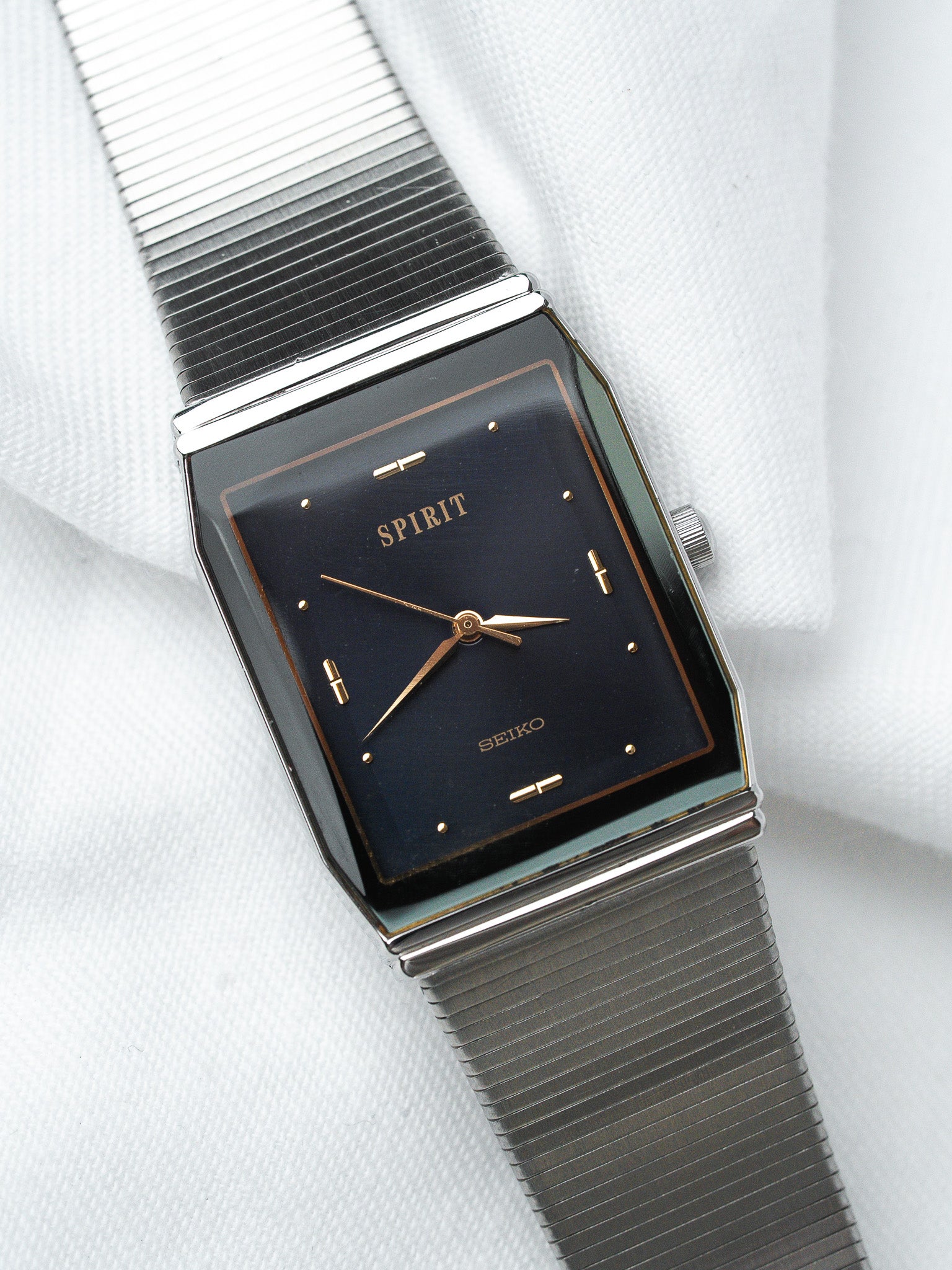 Seiko Spirit vintage watch with black dial, gold markers, and steel mesh bracelet