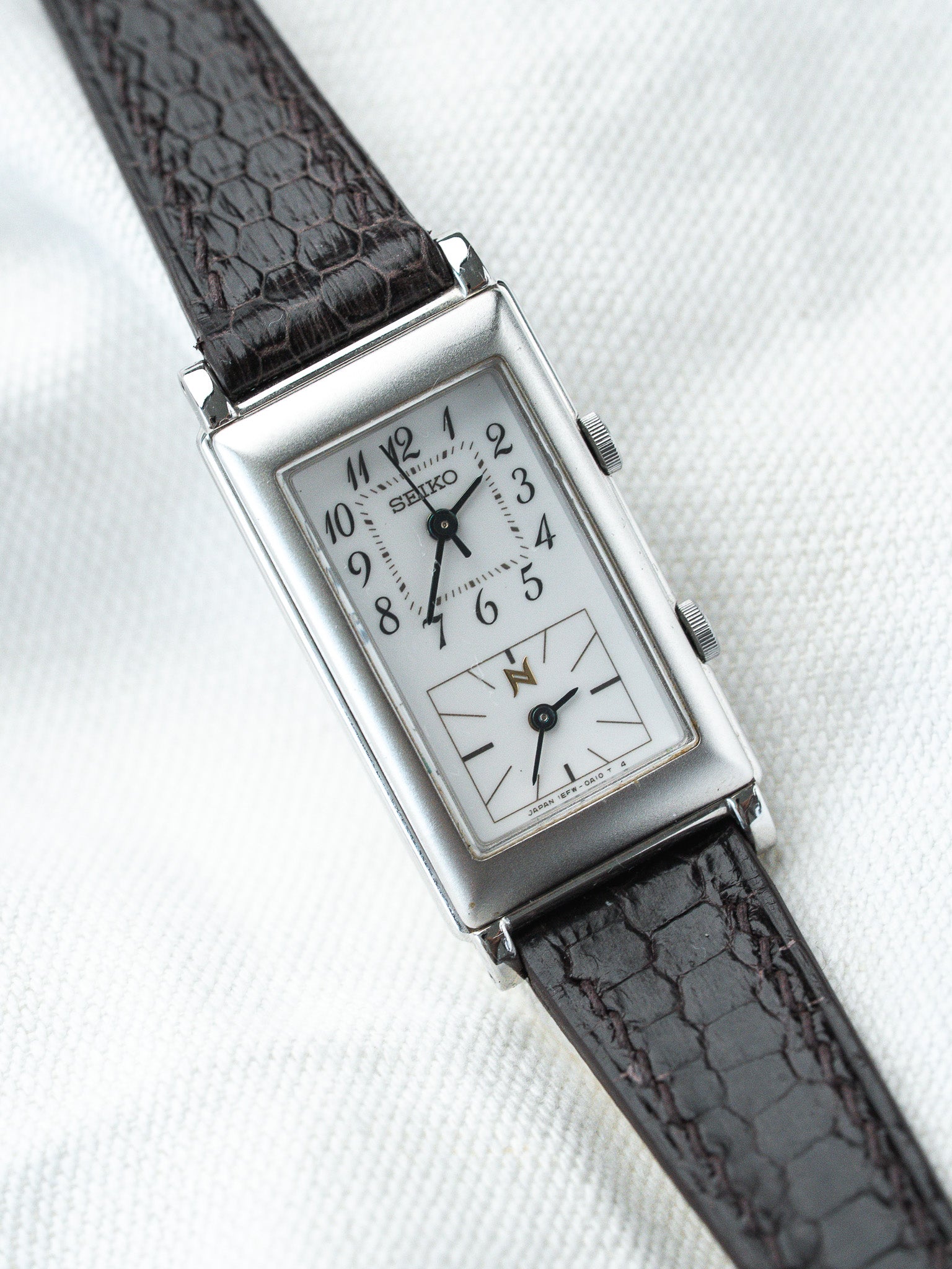 Vintage Seiko rectangular watch with white dial, black numerals, and brown leather strap