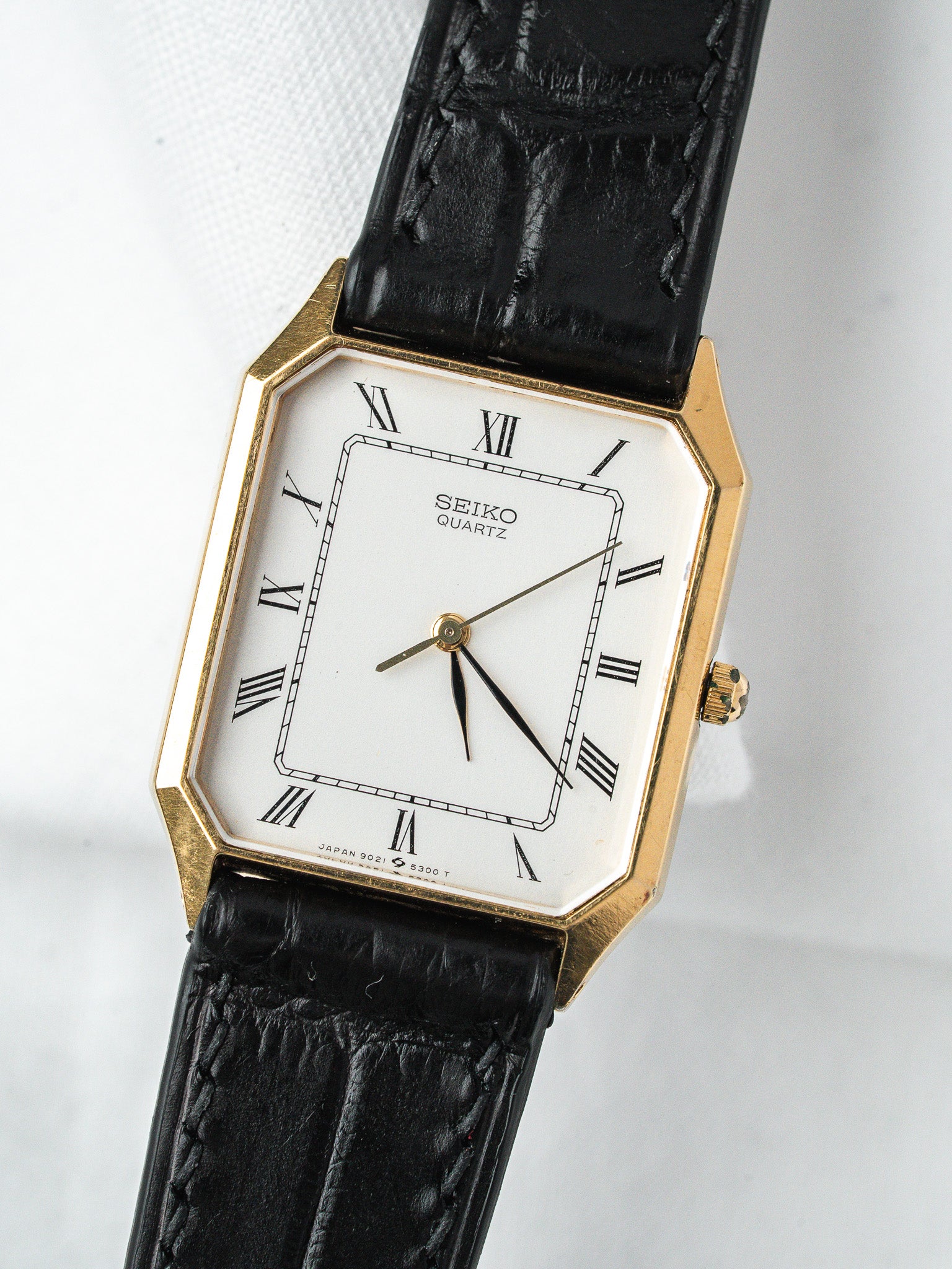 Seiko Quartz vintage watch with gold case, white dial, Roman numerals, black leather strap