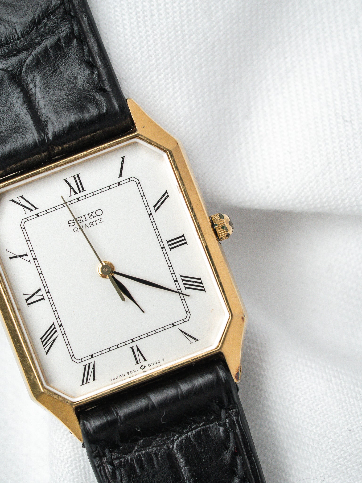 Seiko Quartz vintage watch with gold case, white dial, Roman numerals, black leather strap