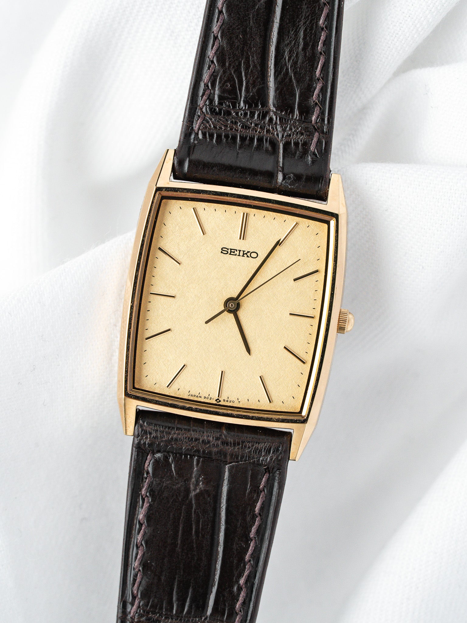 Seiko vintage watch with gold case, cream dial, and dark brown leather strap