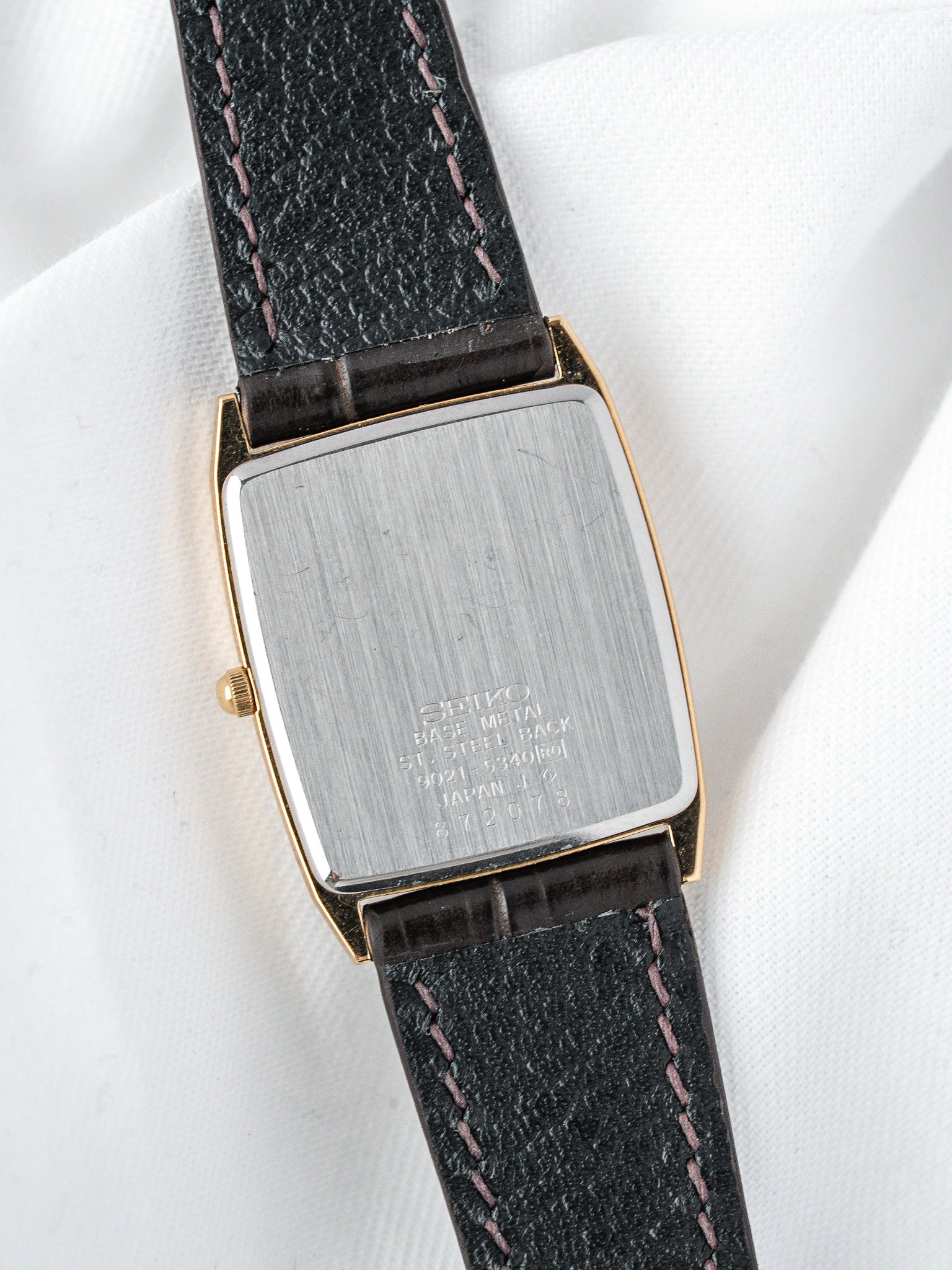 Seiko vintage watch with gold-tone case, black leather strap, and brushed steel back