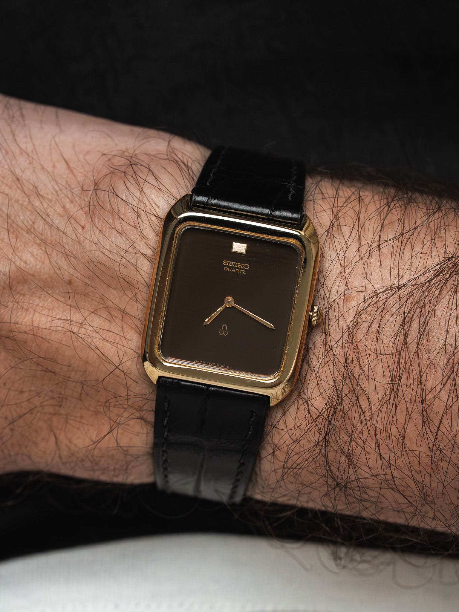 Seiko Quartz vintage watch with gold case, black dial, and leather strap on wrist