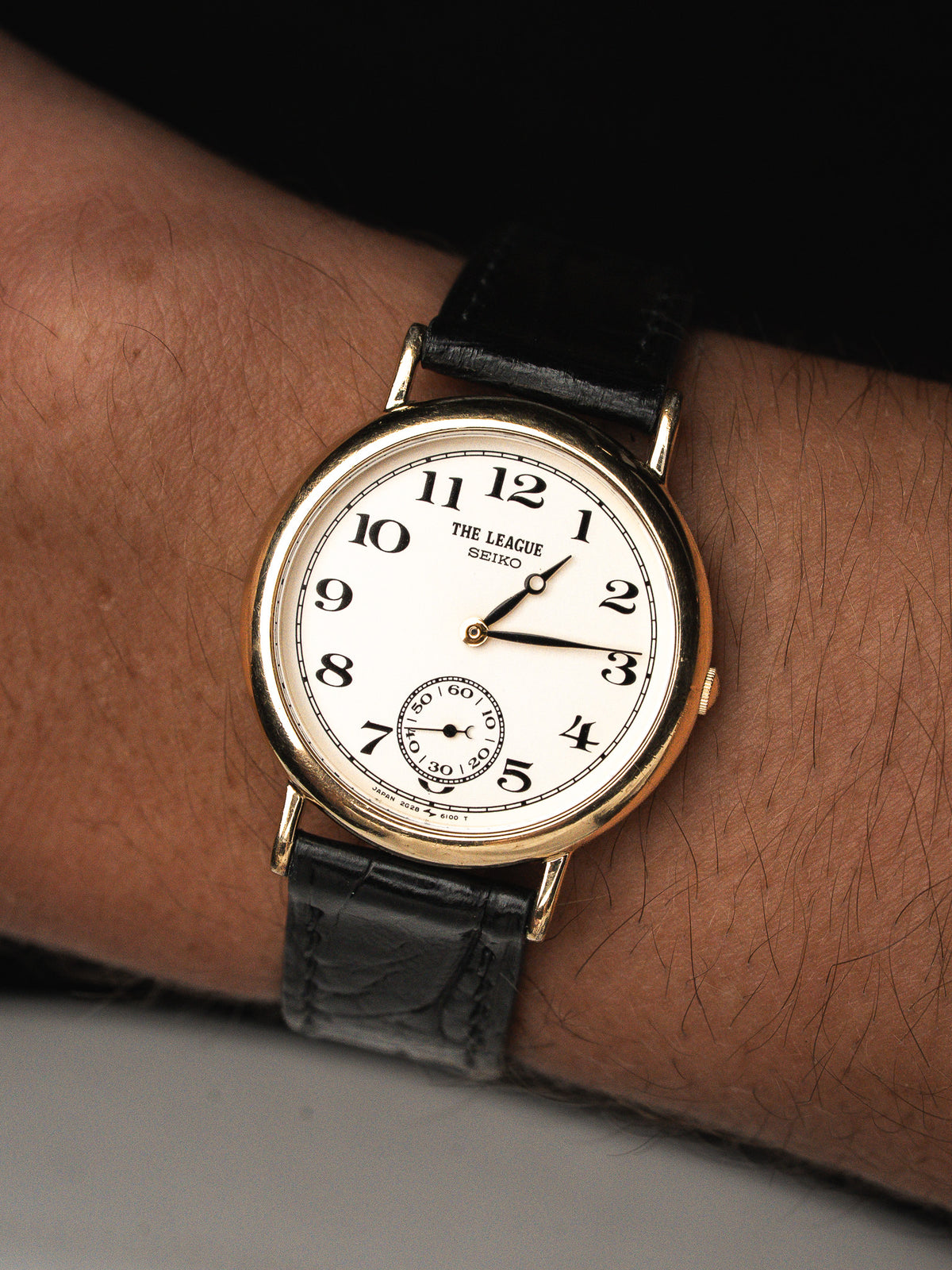 Montre Seiko avec cadran blanc, boîtier doré et bracelet en cuir noir