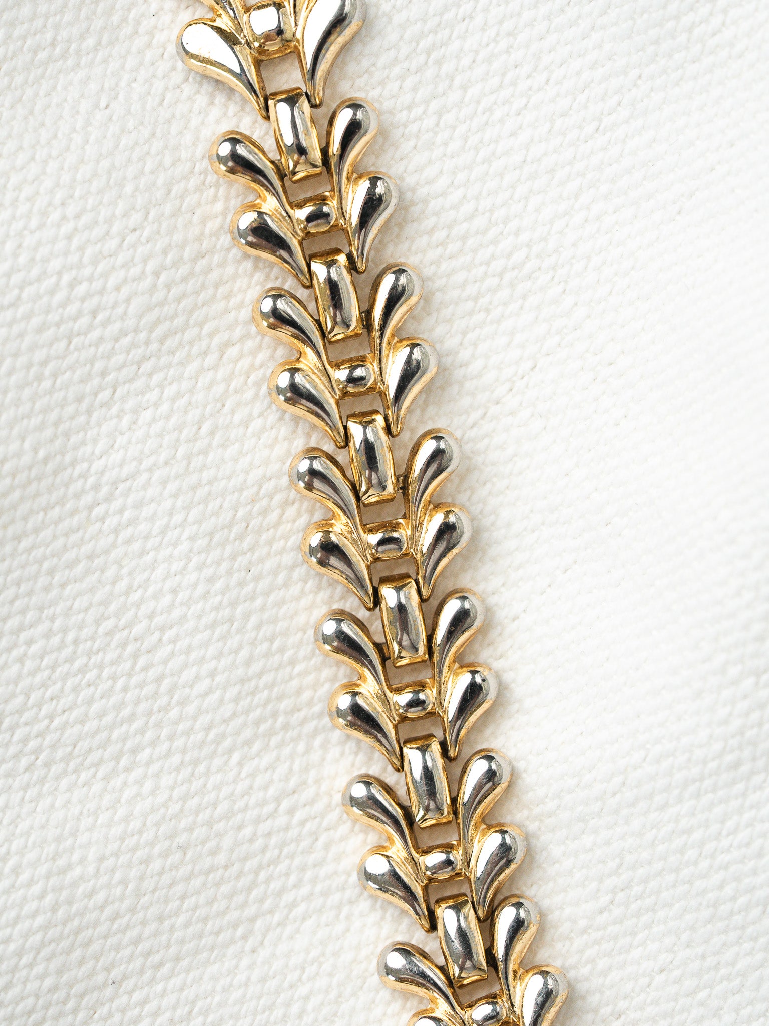 Vintage two-tone gold and silver bracelet with leaf-link design on white textured background