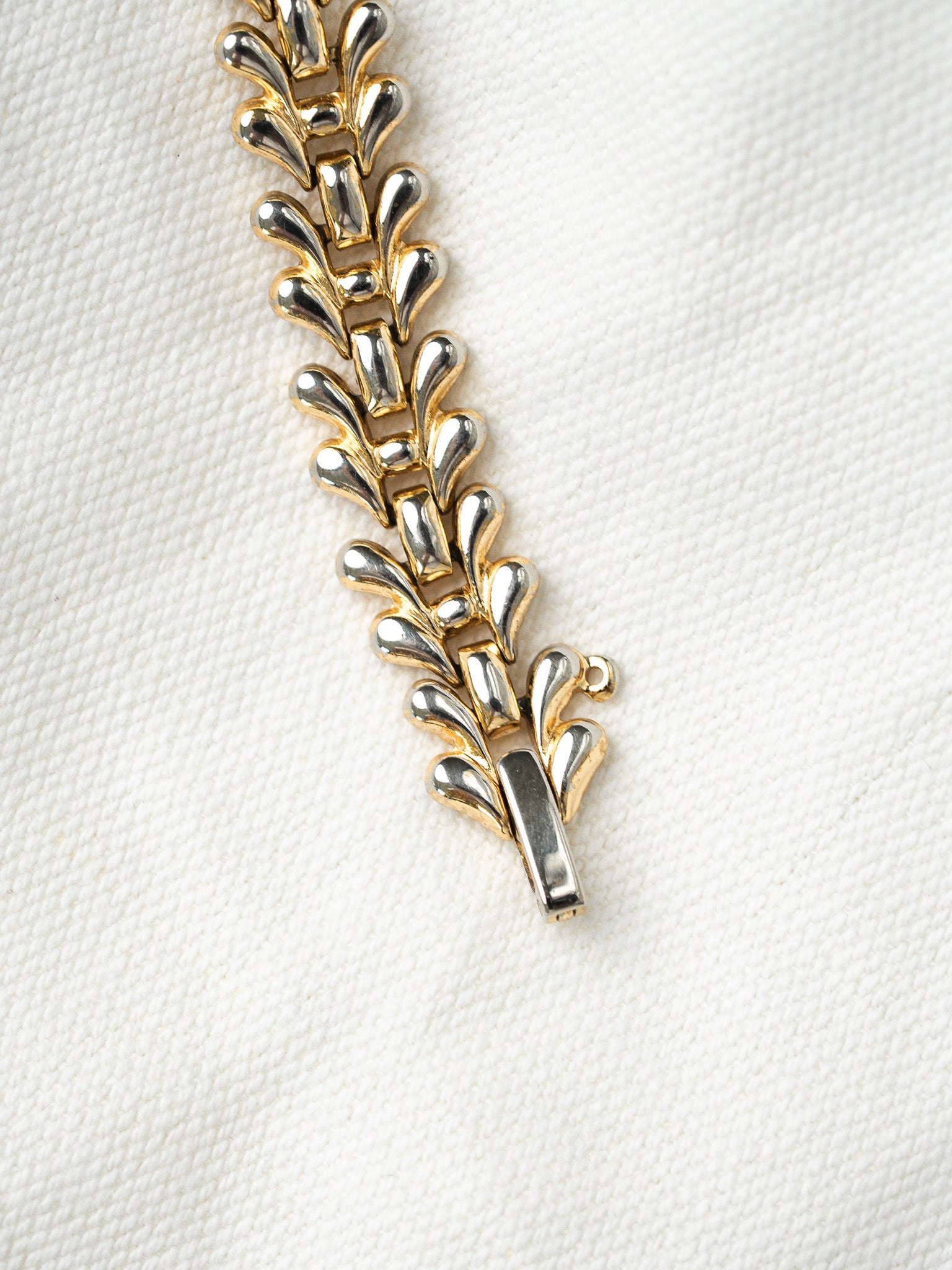 Vintage two-tone bracelet with leaf-shaped links, gold and silver tones on white fabric