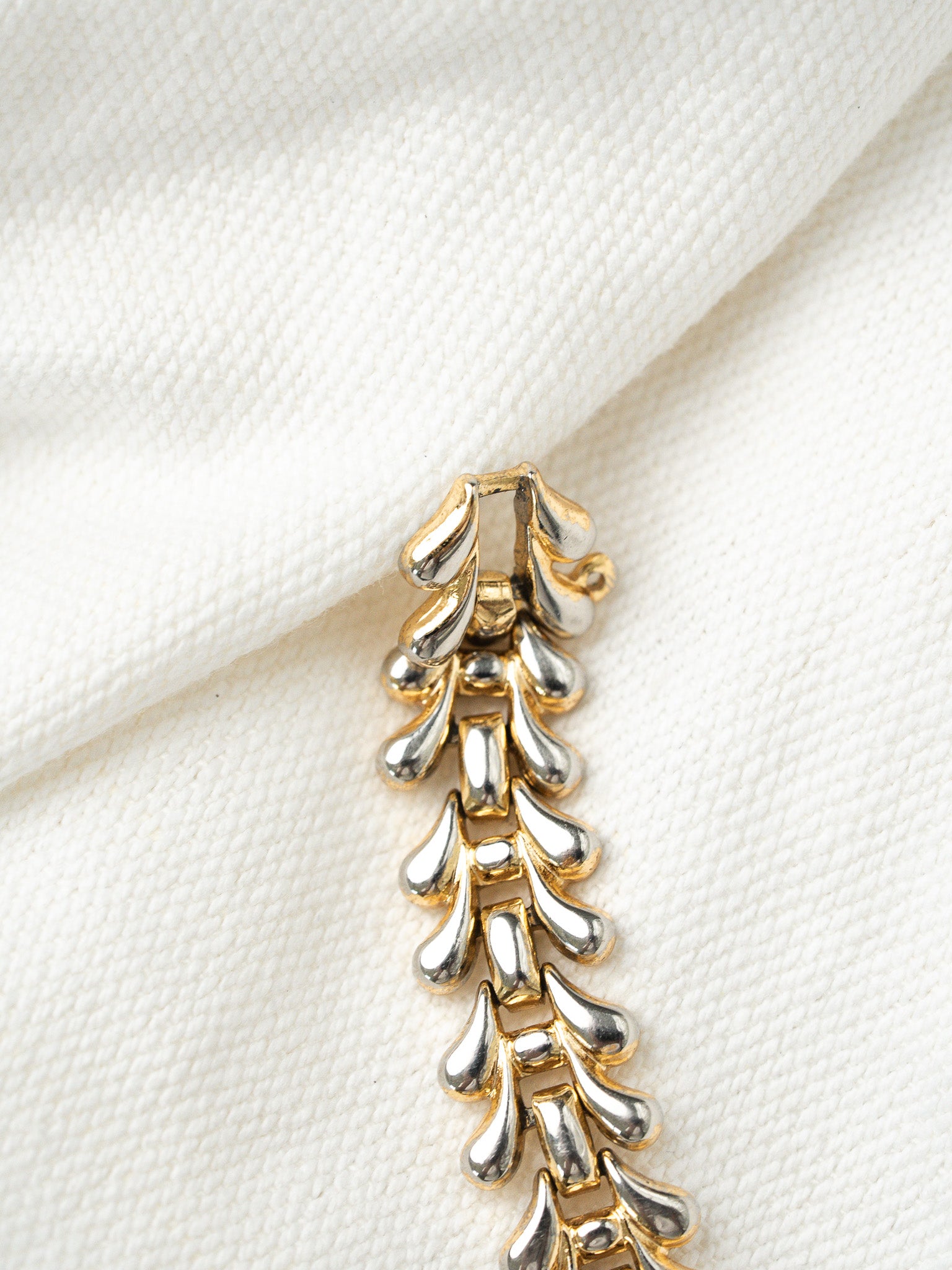 Vintage two-tone gold and silver bracelet with teardrop links on white fabric