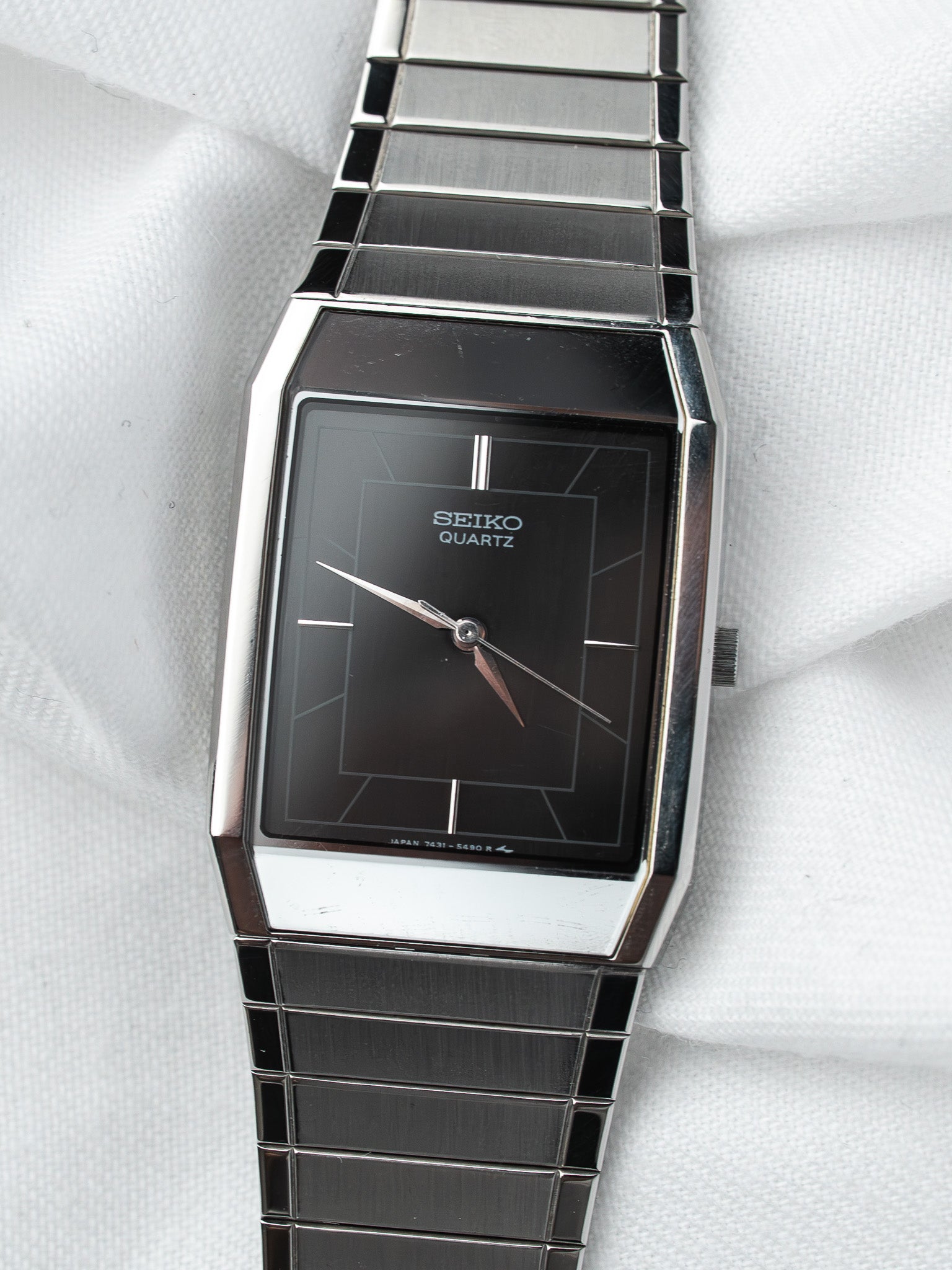 Seiko Quartz vintage watch with black dial, silver case, and metal bracelet on white fabric