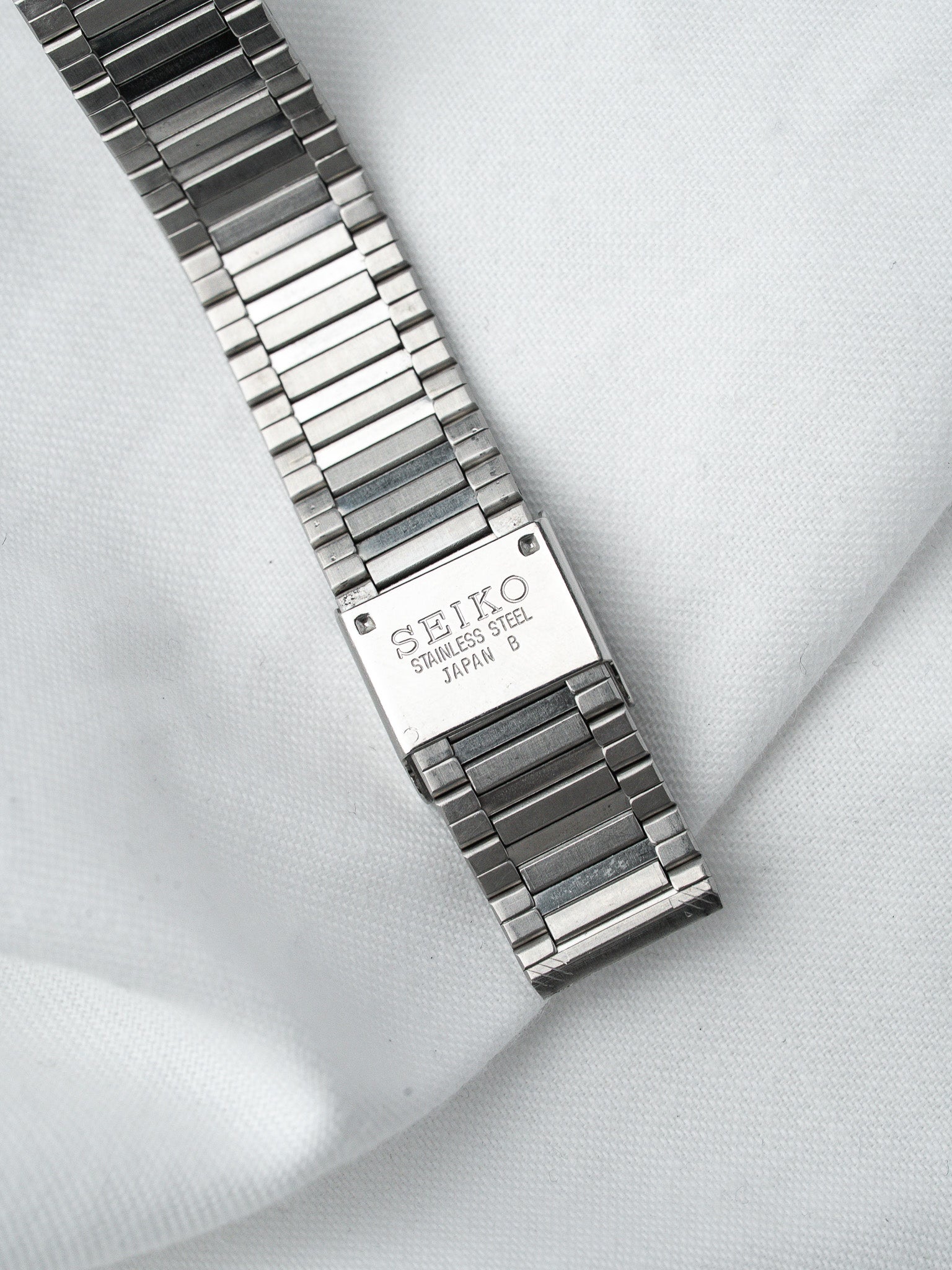 Seiko vintage stainless steel watch bracelet with engraved clasp on white fabric
