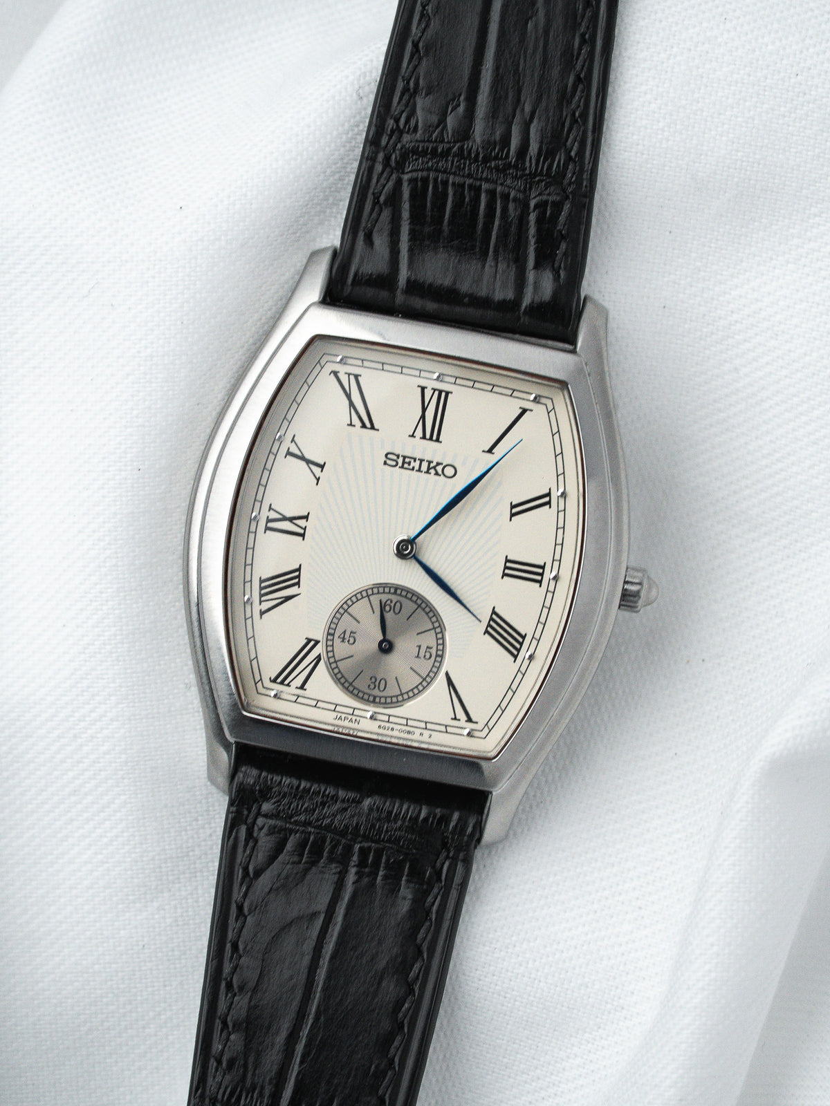 Seiko vintage watch with silver case, white dial, Roman numerals, black leather strap