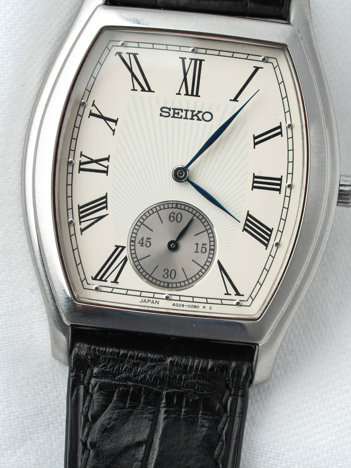 Seiko vintage watch with silver case, white dial, Roman numerals, black leather strap