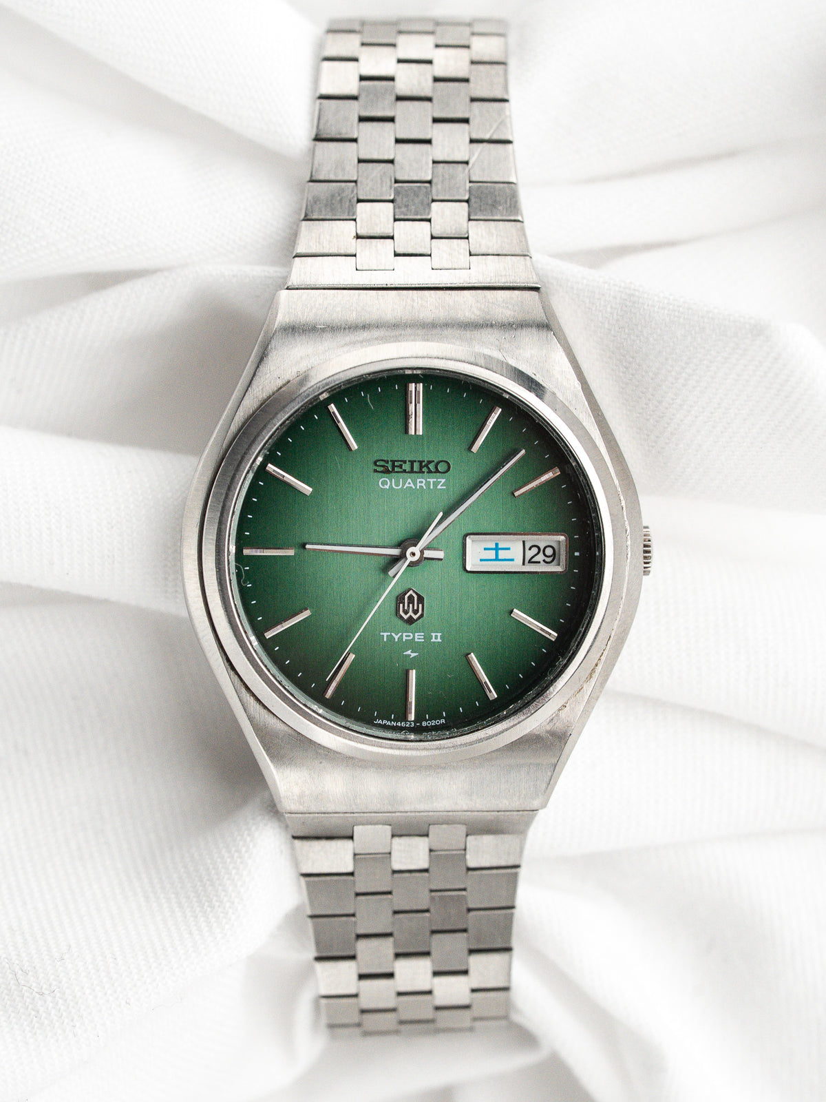 Montre Seiko Quartz vintage avec cadran vert et bracelet en acier argenté.