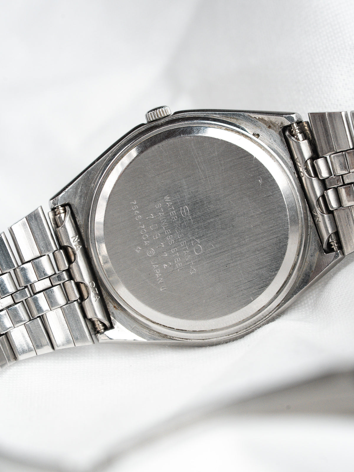 Seiko 5 vintage stainless steel watch back with engraved details on white fabric