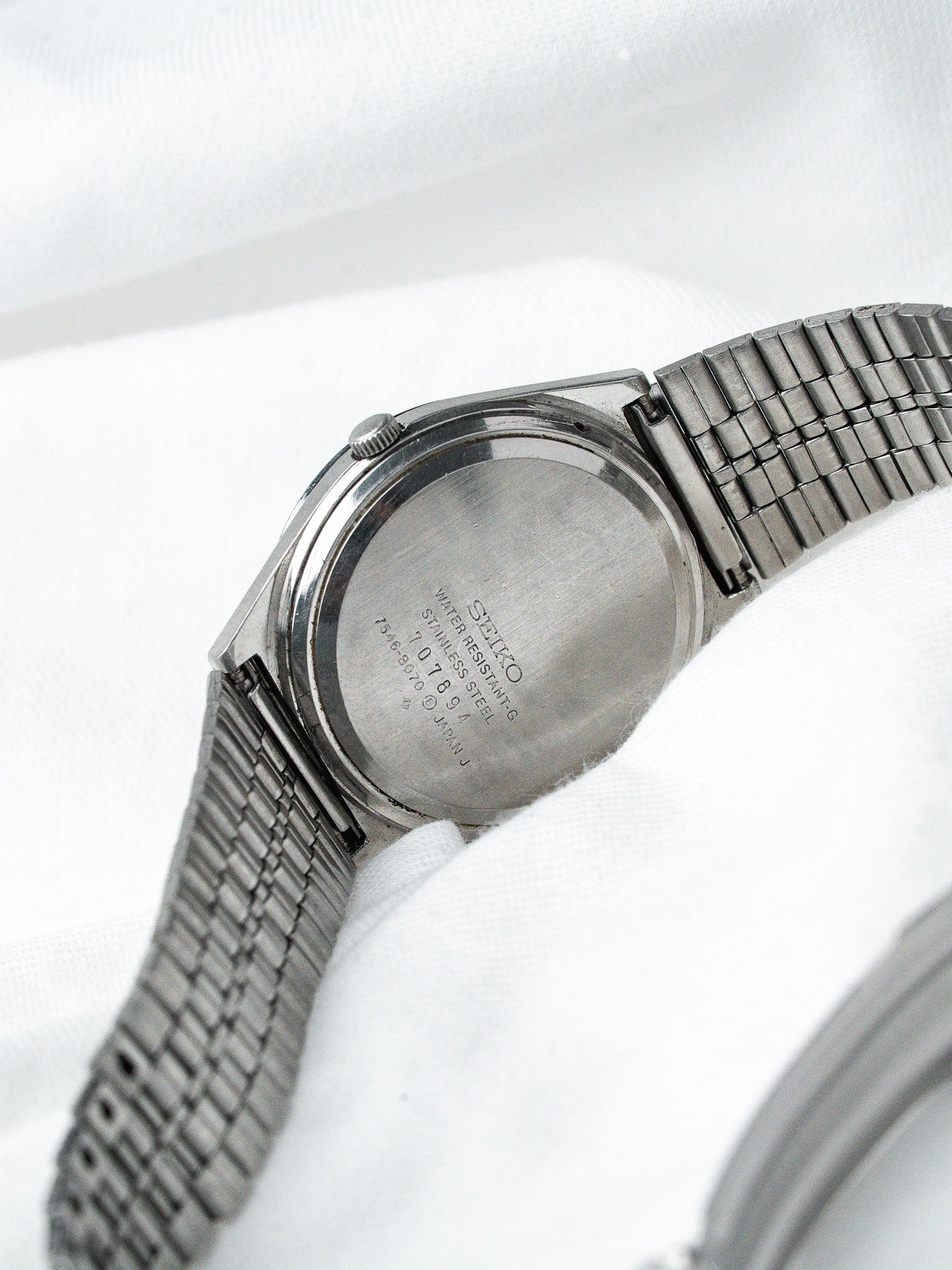 Seiko vintage watch back, stainless steel case, mesh bracelet on white fabric