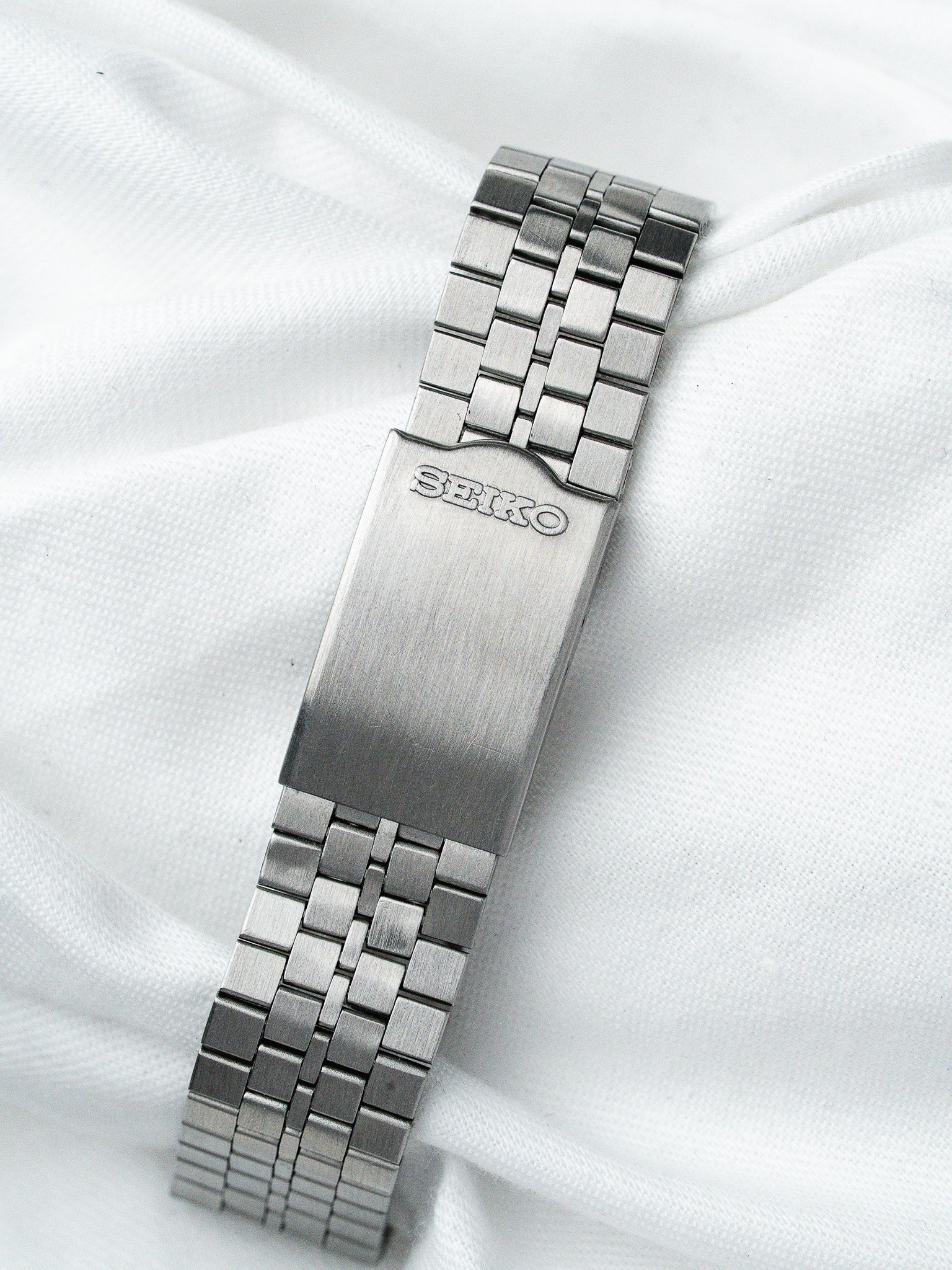 Seiko vintage steel bracelet with brushed finish, laid on white fabric