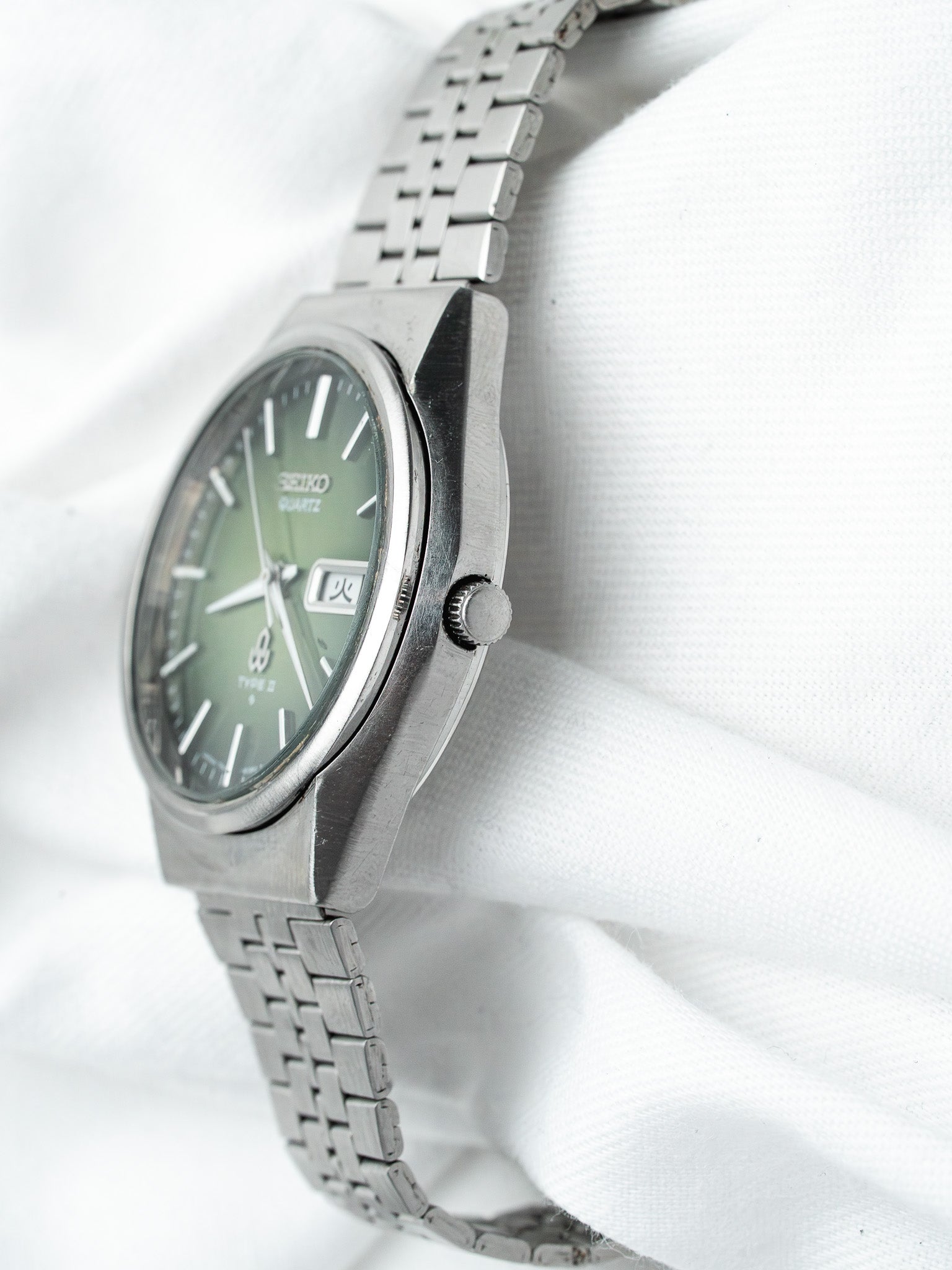 Seiko Quartz vintage watch with green dial, steel case and bracelet on white fabric