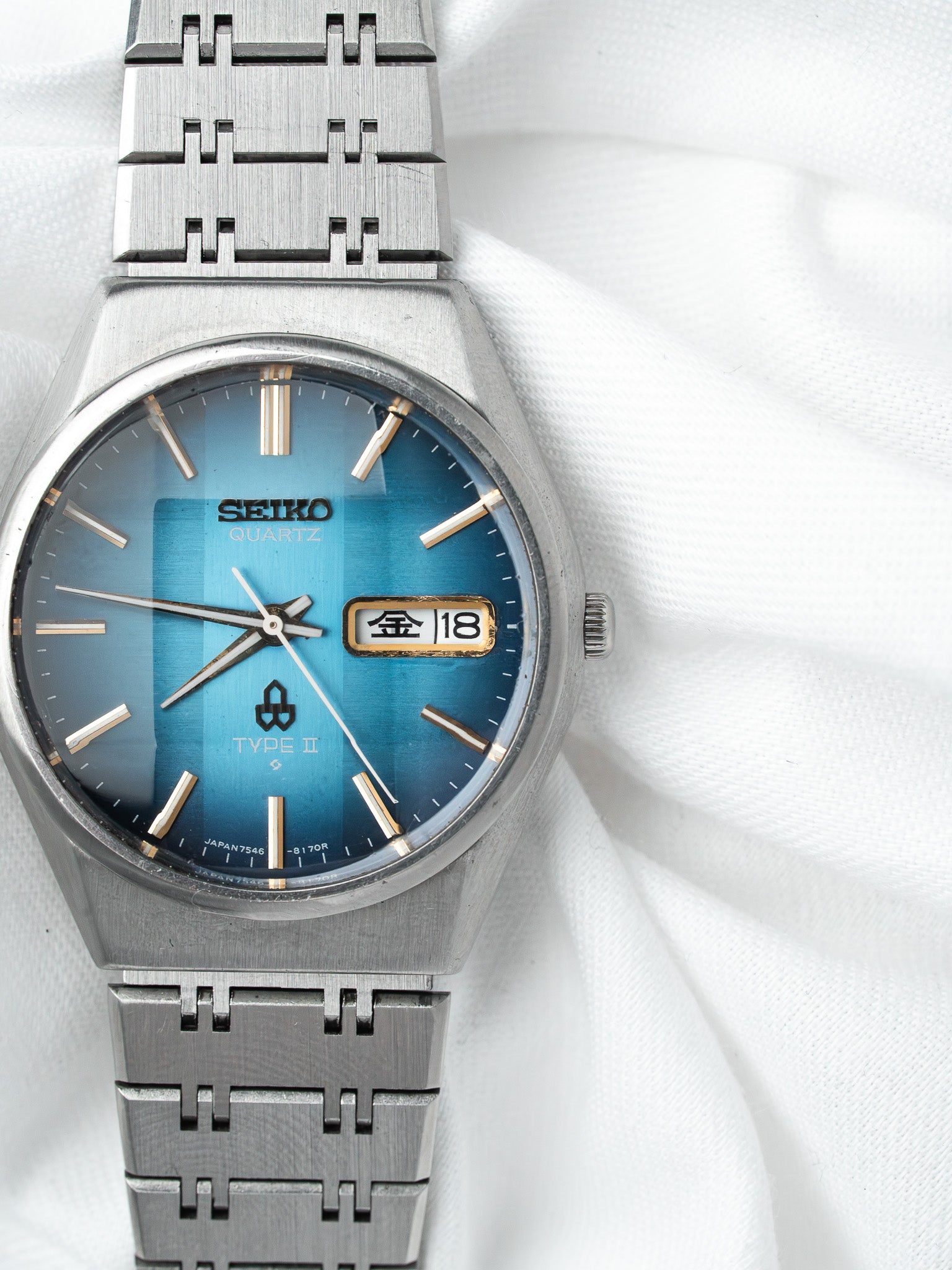 Seiko Quartz Type II vintage watch with blue gradient dial and steel bracelet on white fabric