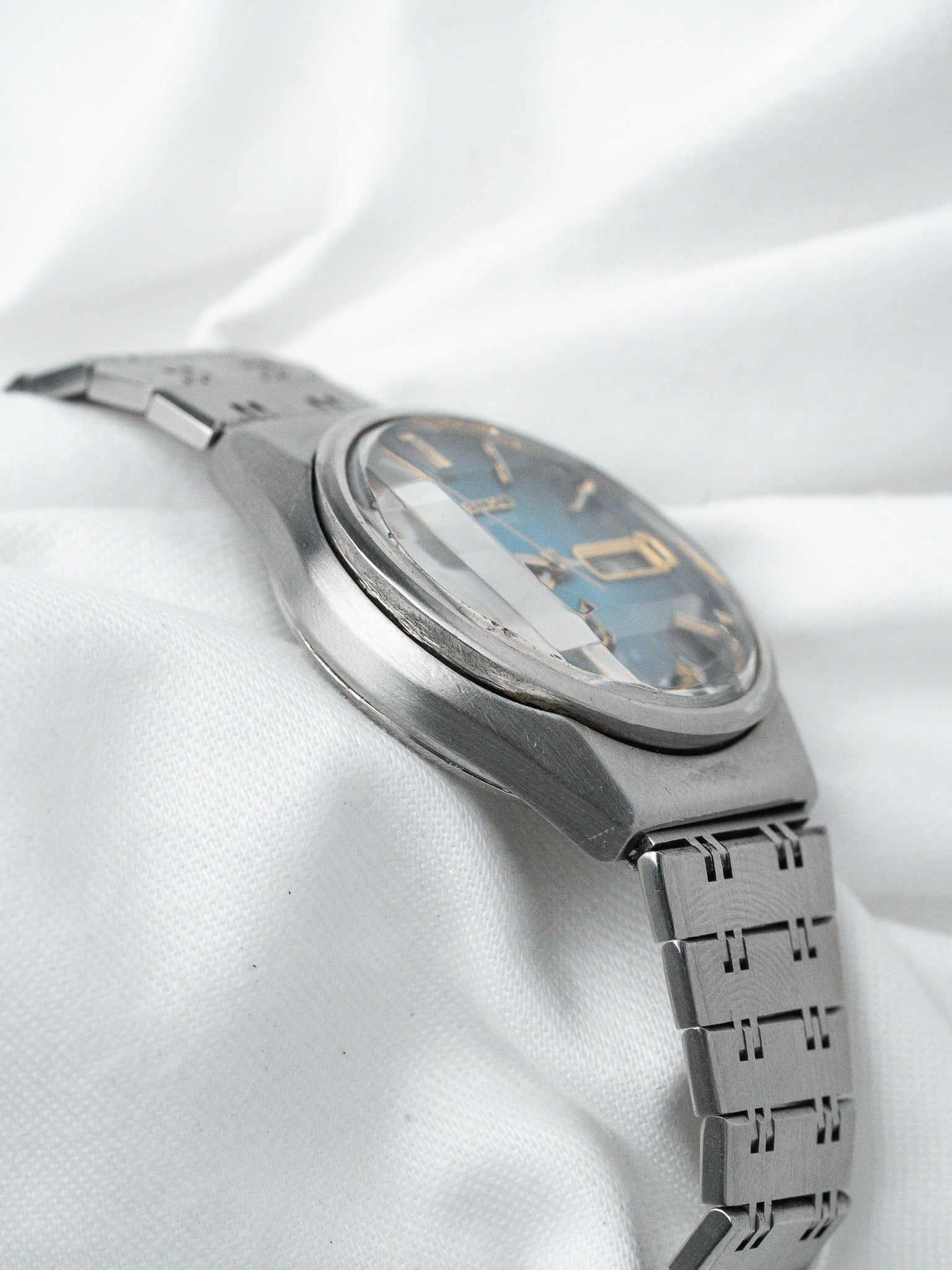 Vintage Seiko watch with blue dial and stainless steel bracelet on white fabric