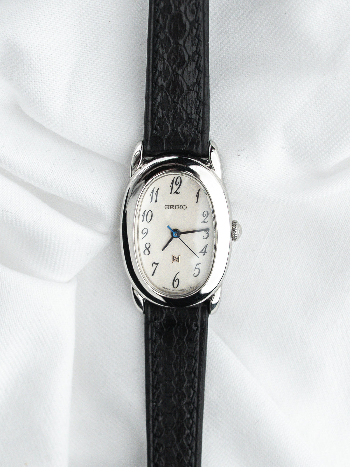 Montre Seiko vintage, boîtier ovale en acier, cadran blanc et bracelet cuir noir