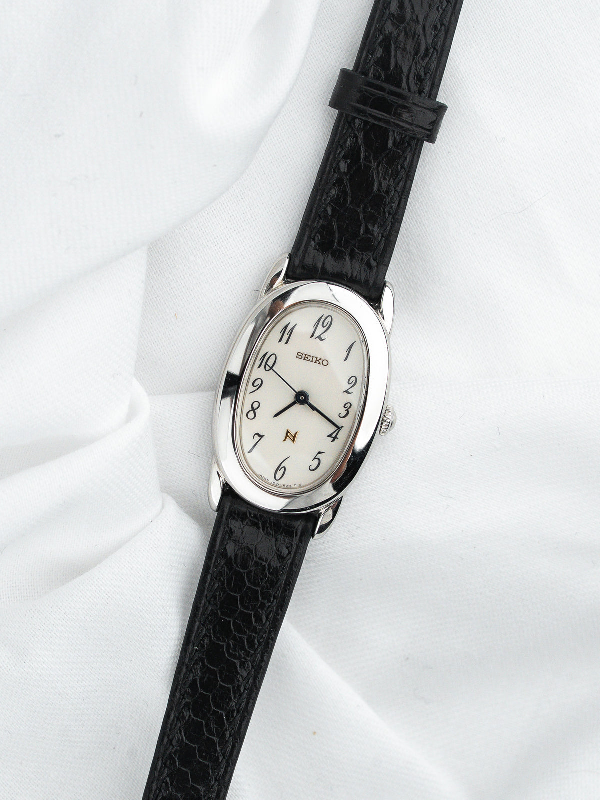 Montre Seiko vintage, boîtier ovale argenté, cadran blanc et bracelet cuir noir