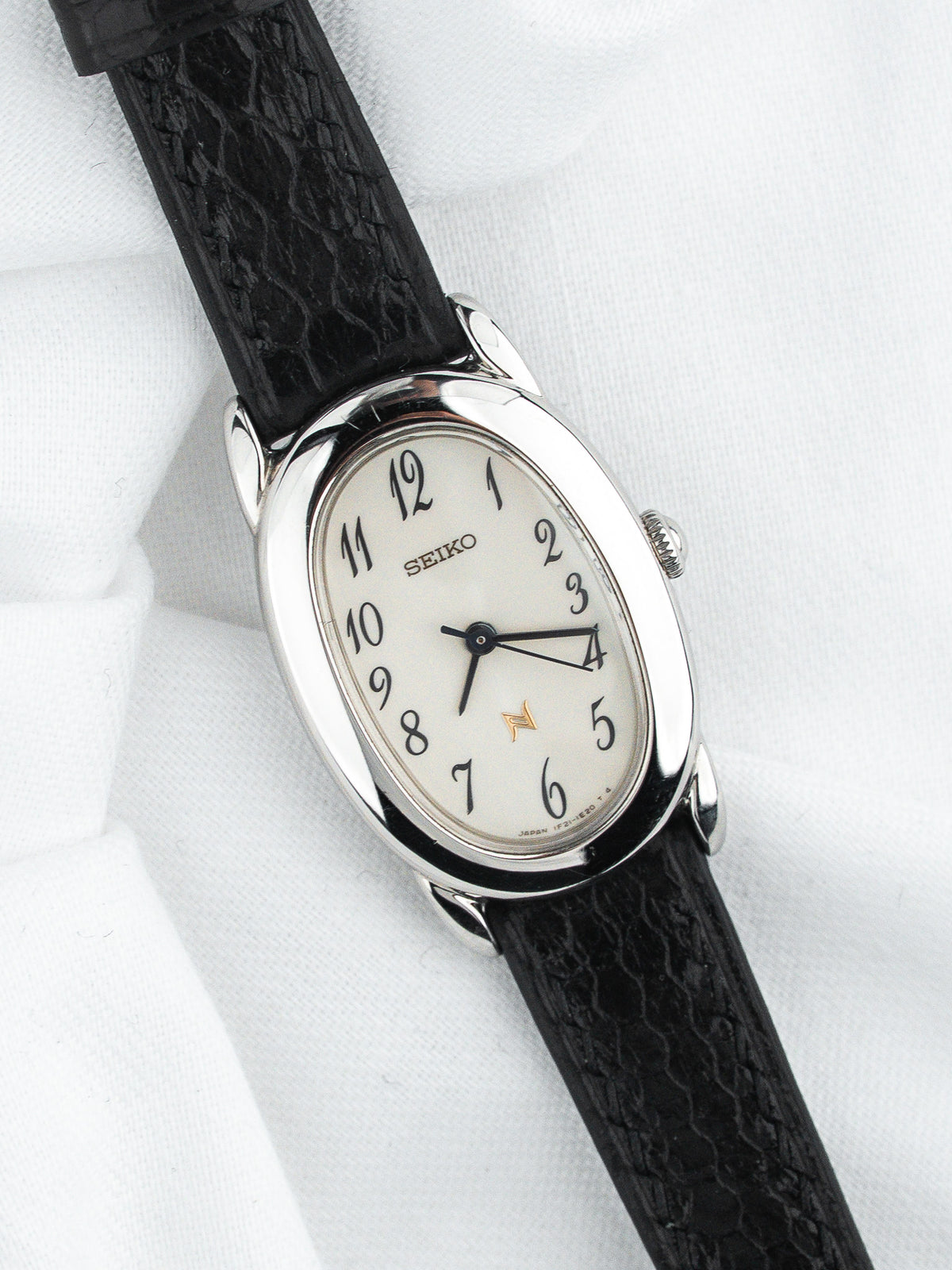Montre Seiko vintage, boîtier ovale argenté, cadran blanc et bracelet cuir noir