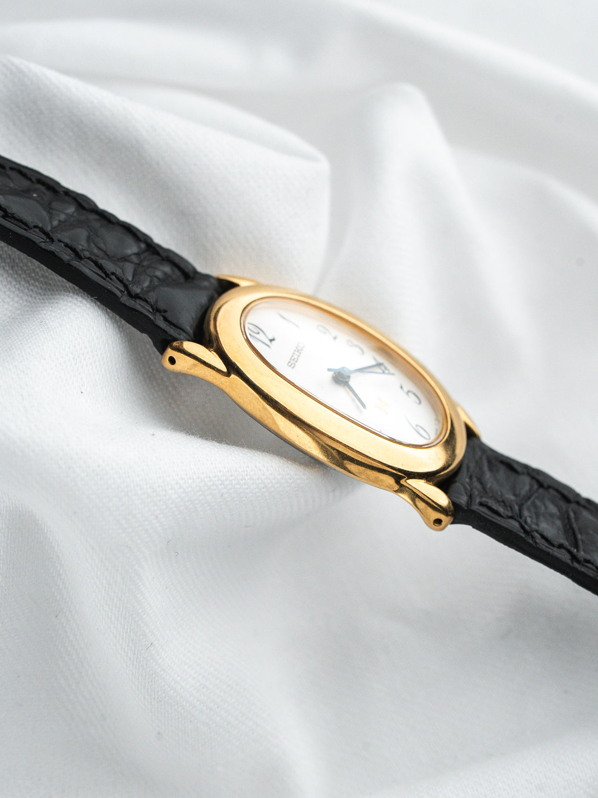 Montre Seiko vintage, boîtier ovale plaqué or, cadran blanc et bracelet cuir noir