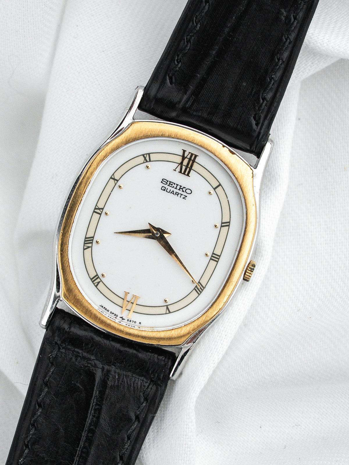Montre Seiko Quartz vintage, boîtier ovale doré, cadran blanc et bracelet cuir noir