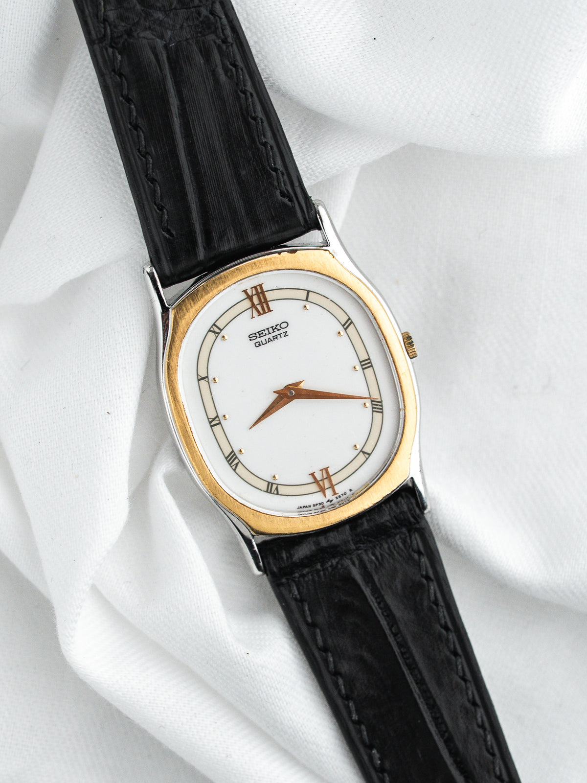 Montre Seiko Quartz vintage, boîtier doré ovale, cadran blanc et bracelet cuir noir